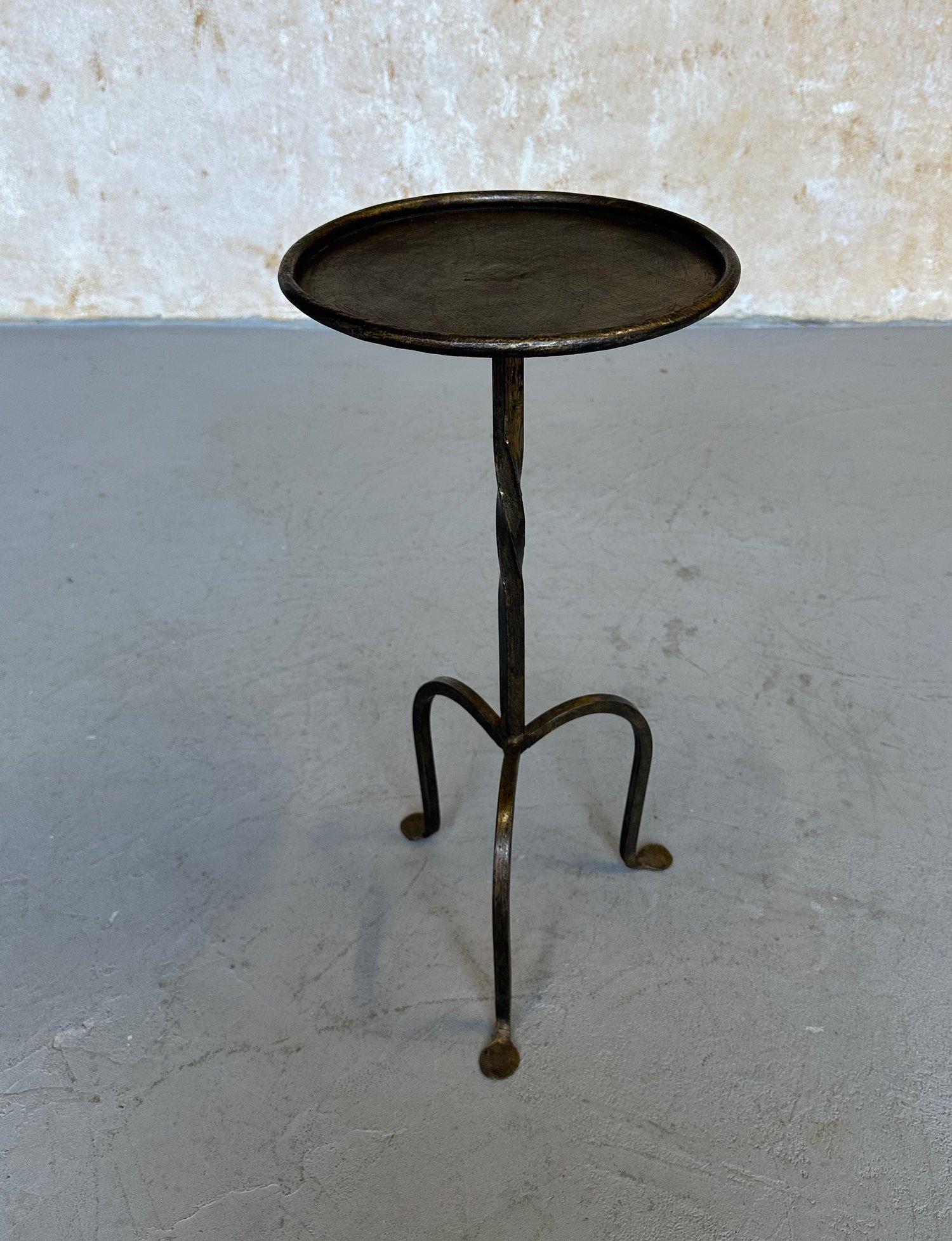Esta encantadora mesa de bebidas española ha sido elaborada a mano por expertos artesanos europeos mediante técnicas tradicionales de trabajo del hierro. Presenta un tallo central elegantemente retorcido sobre una base trípode con pies suavemente