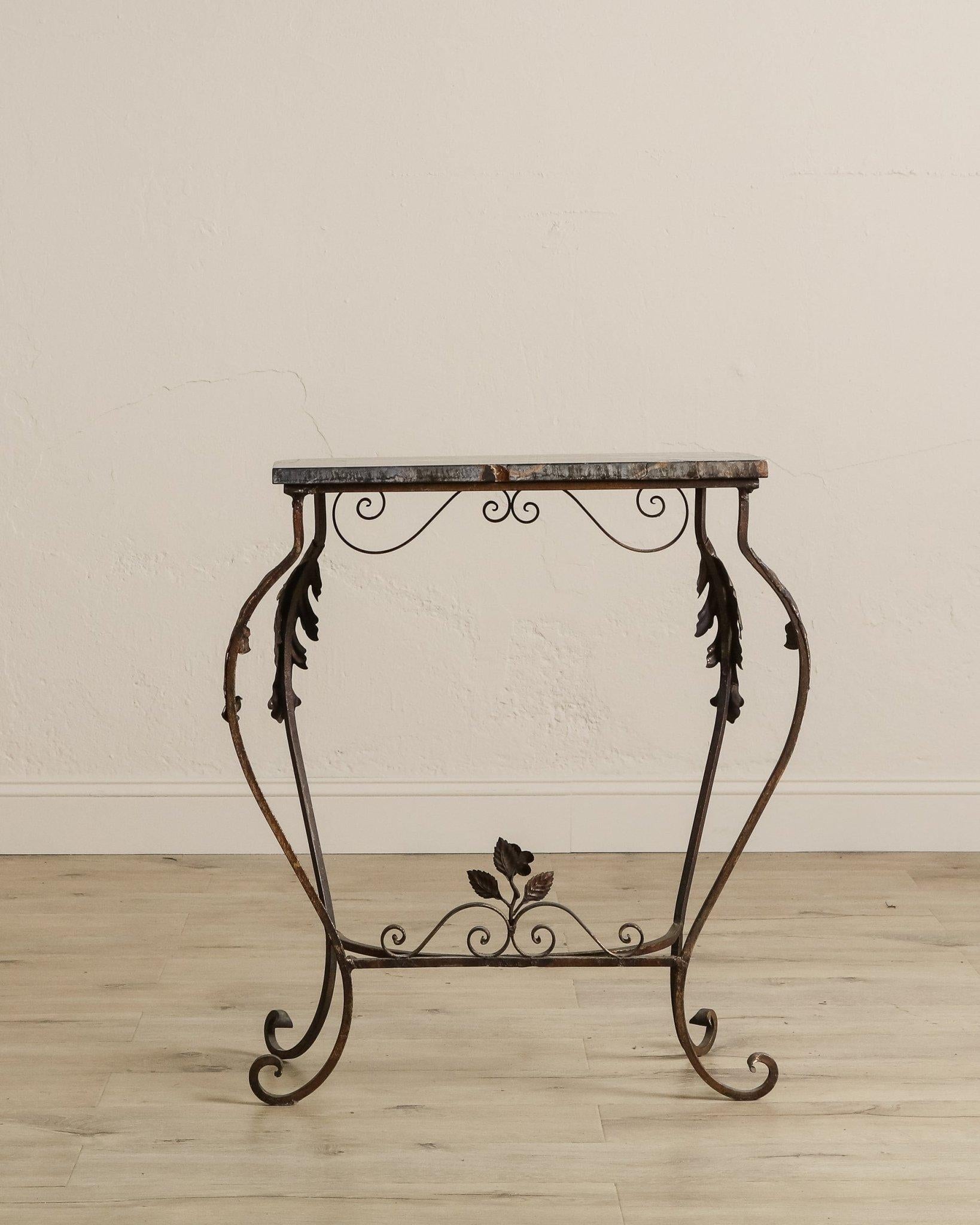Realizzato con maestria negli anni '20, questo elegante tavolo demilune esemplifica la raffinata maestria del design decorativo dei primi anni del XX secolo. La struttura in ferro battuto a mano presenta intricati dettagli a foglie d'acanto e un