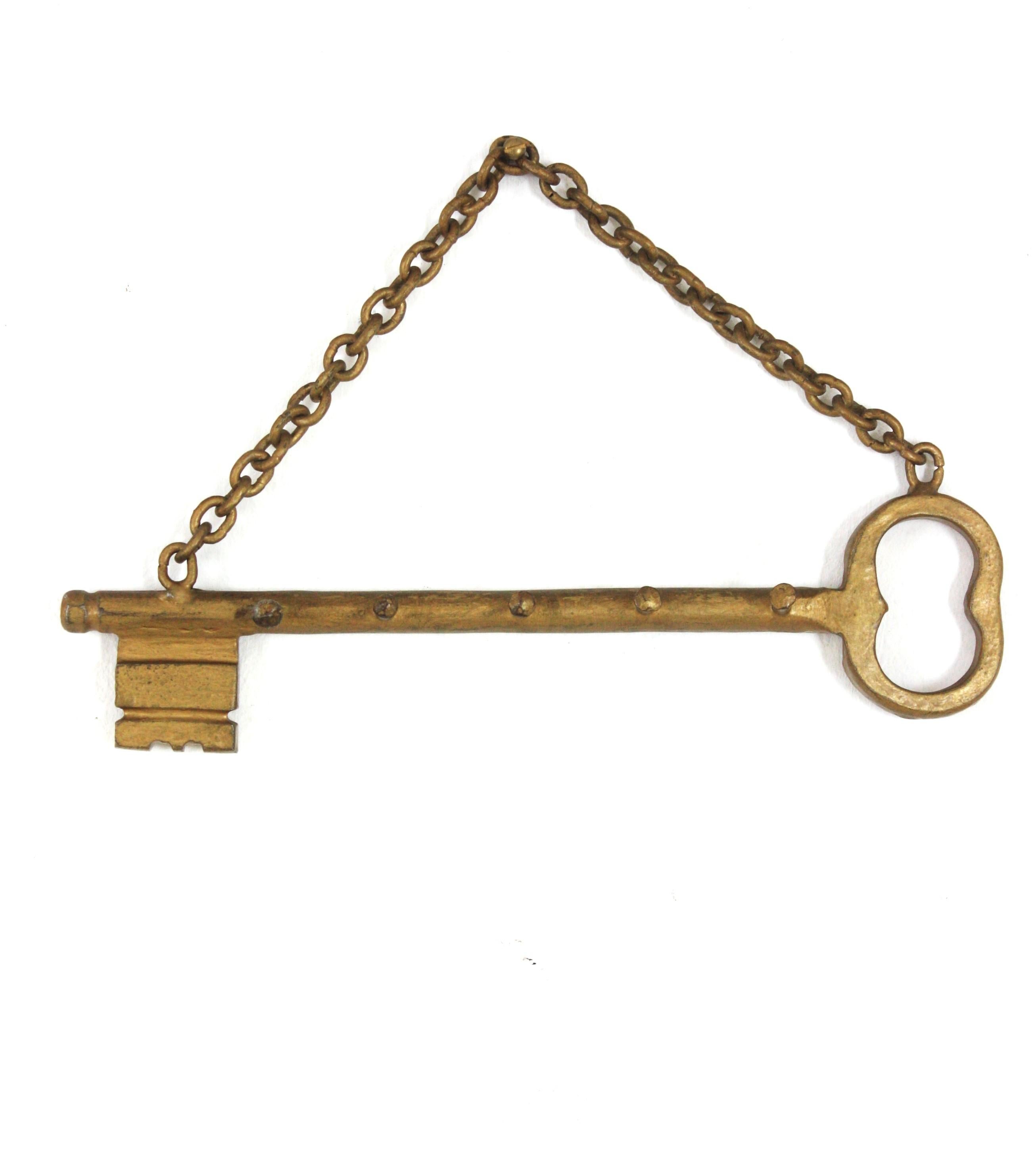 Key Shaped Wall Key Hanger, Spain, 1940-1950.
Eye-catching vintage midcentury key holder with key shape hanging from a chain and 5 hangers.
Hand forged in iron and finished in gilt patina.
Great vintage condition. 
It can be used as key hanger or as