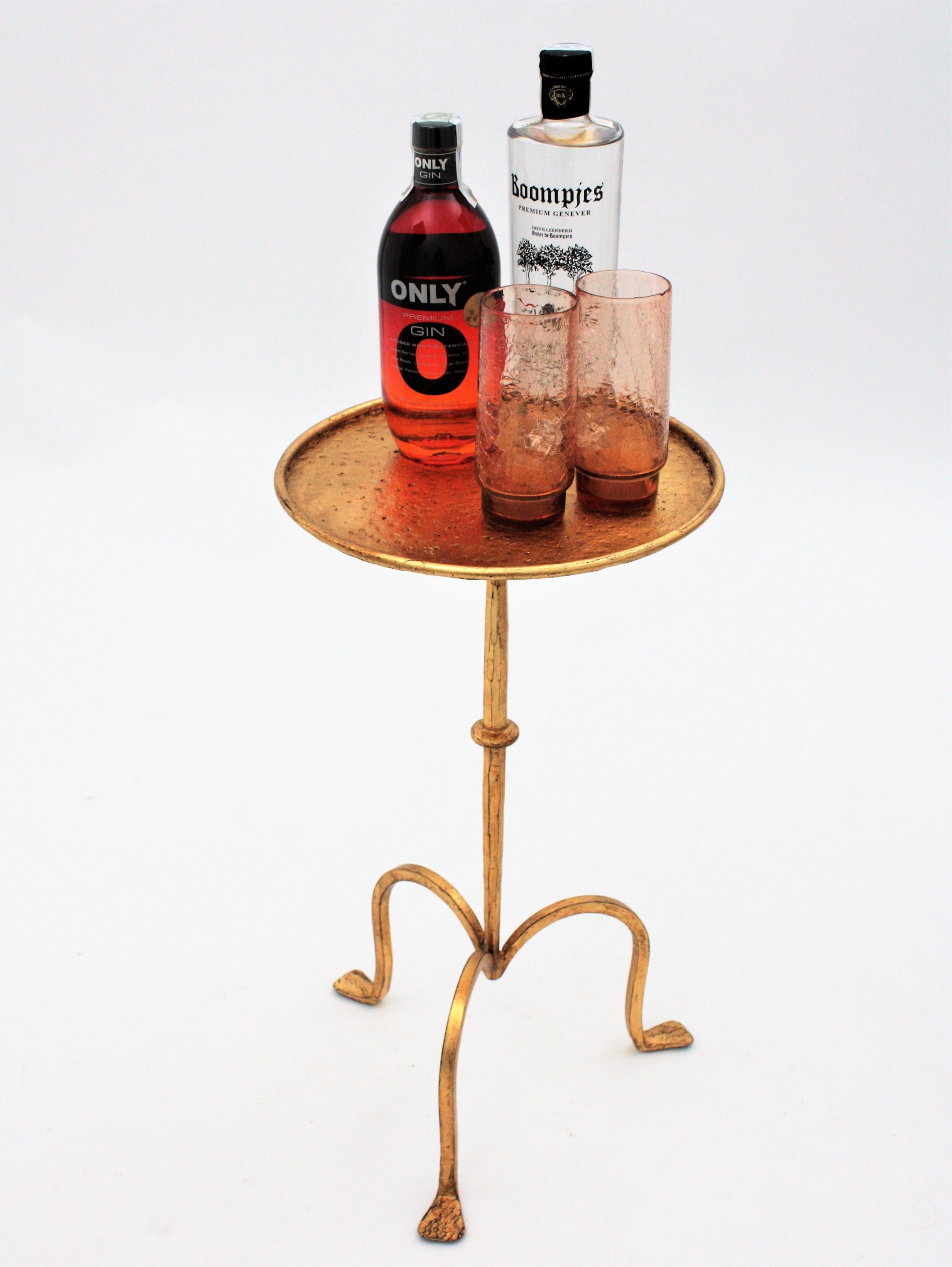 Beautiful hand-hammered 58 cm height gold leaf gilt iron occasional drinks table on a tripod base. Spain, 1940s-1950s.
This gueridon was manufactured at the Mid-Century Modern period with Gothic style accents. It has a decoration with Hammer marks