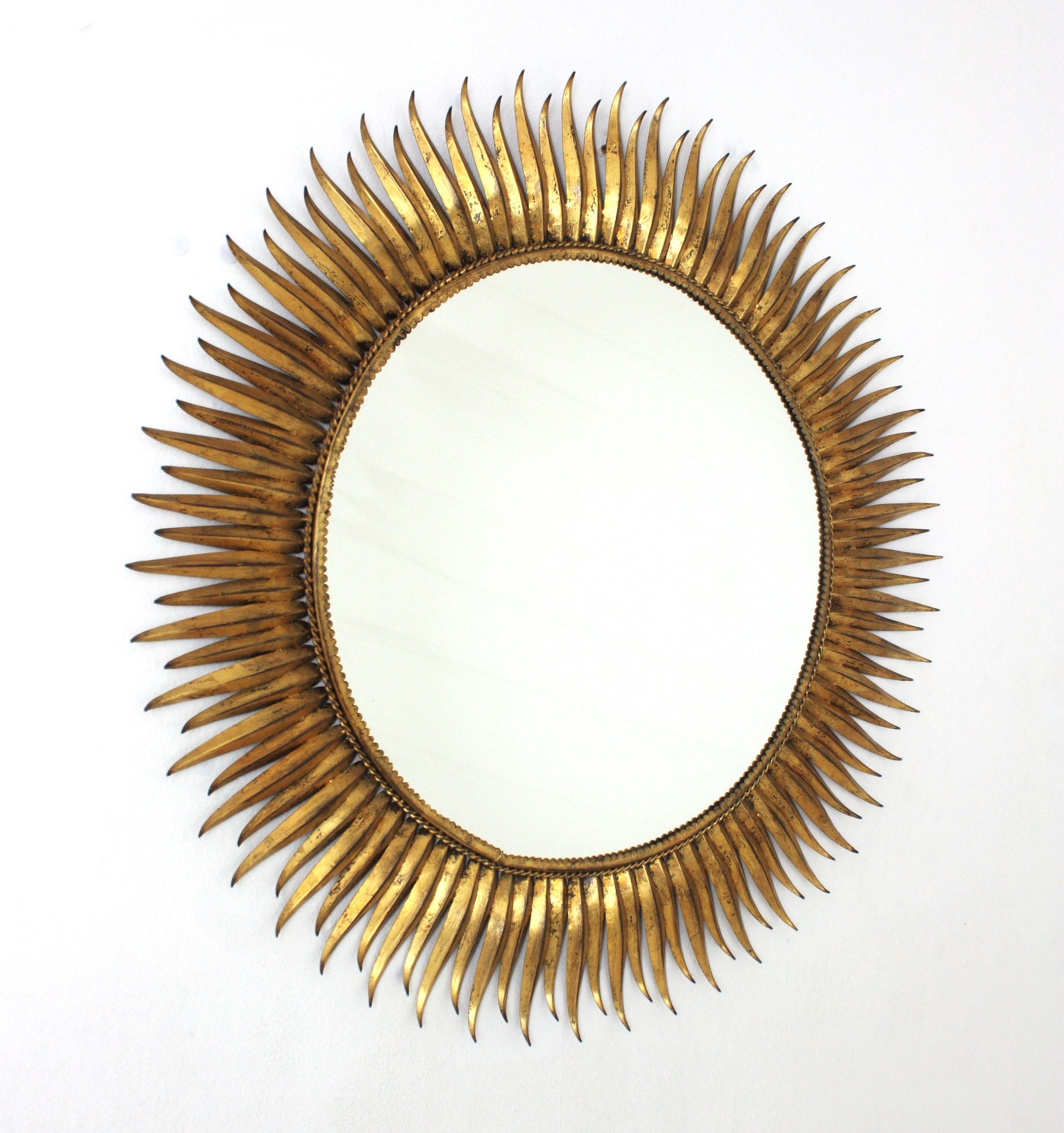 Outstanding Large scale gilt iron eyelash sunburst mirror. Spain, 1950s
The frame is made is entirely made by hand with alternating hand-hammered curved and straight rays in eyelash shape. Finished in gold leaf. Gorgeous gilding and patina.
This XL