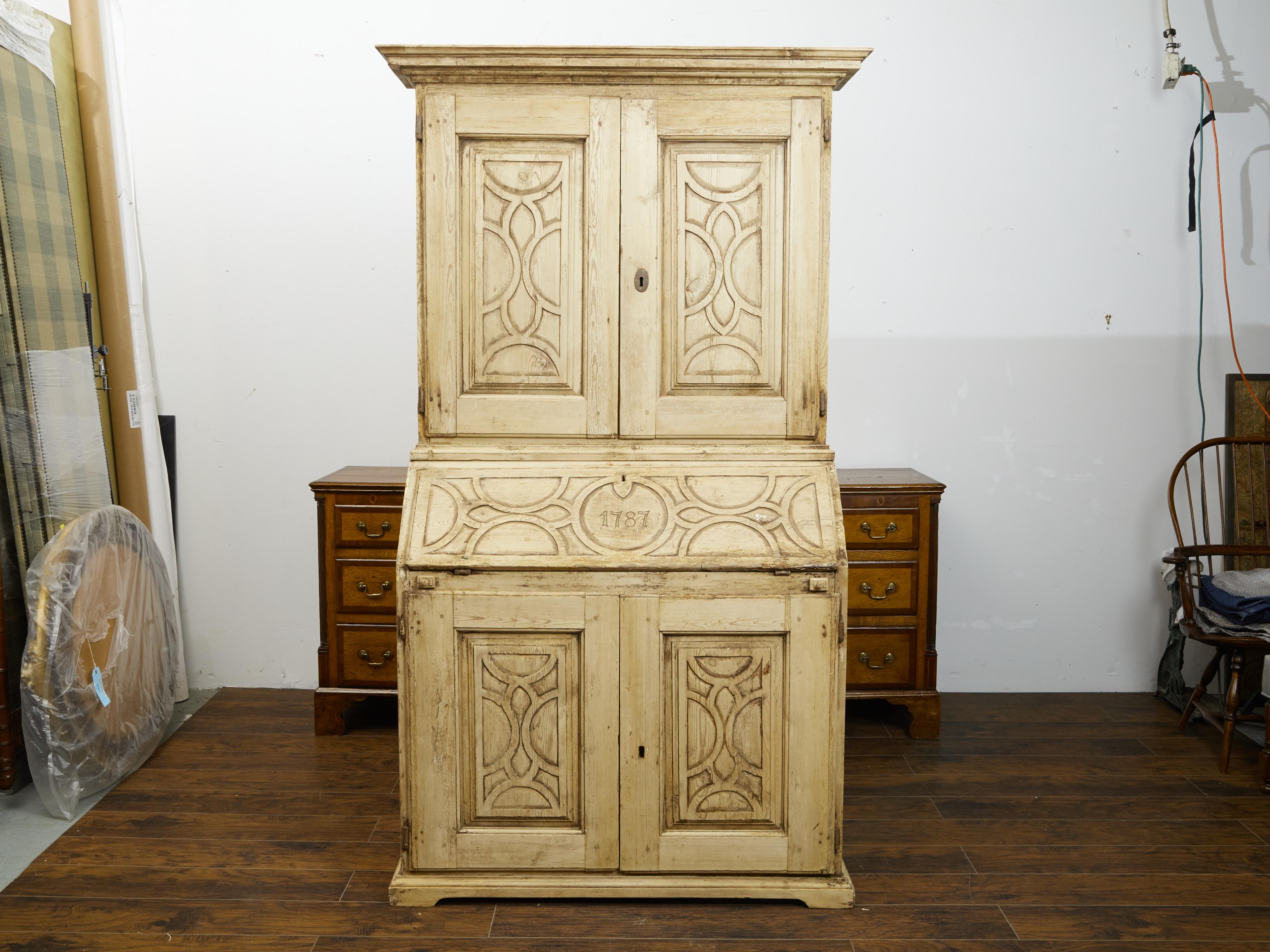 A Spanish pine tall secretaire from the late 18th century, with carved date, slanted desk and geometric panels. Created in Spain during the last quarter of the 18th century, this tall pine secretaire features a molded cornice sitting above two doors