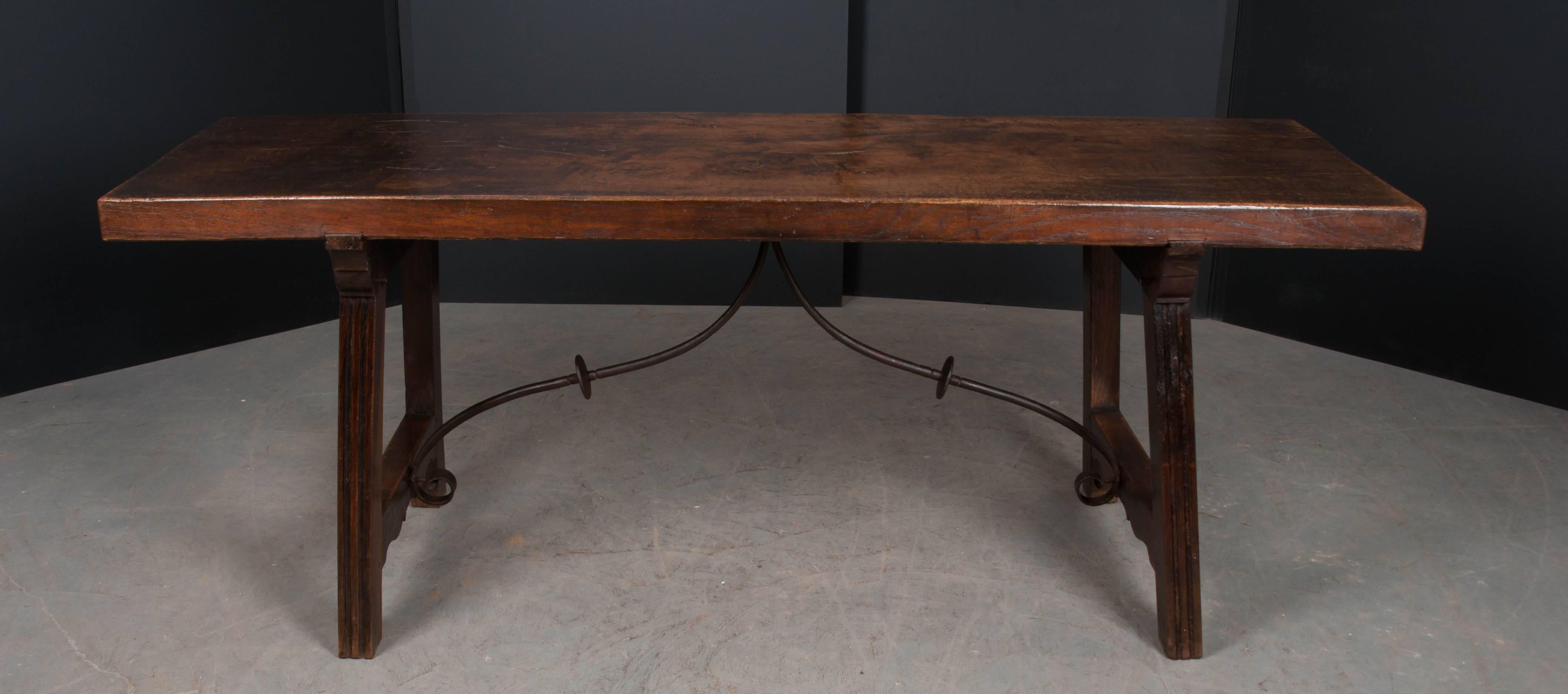 A magnificent hardwood refectory dining table, made in Spain, circa 1780. The table’s top is made from a single, hefty board. The top is supported by A-frame uprights that are kicked out and braced with scrolled iron stretchers. The table has