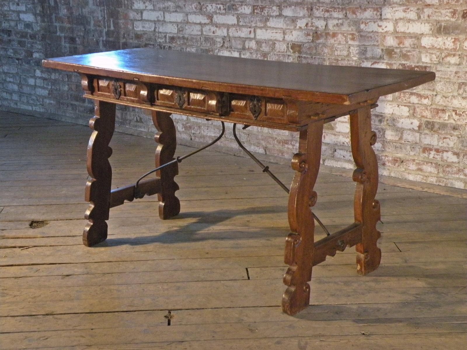 Mesa de escritorio rústica del Barroco tardío español, de castaño, con una maravillosa pátina cálida y profunda y una sobria decoración en los paneles de los cajones delanteros.
La mesa, con tablero de una lama, sobre un friso que contiene tres