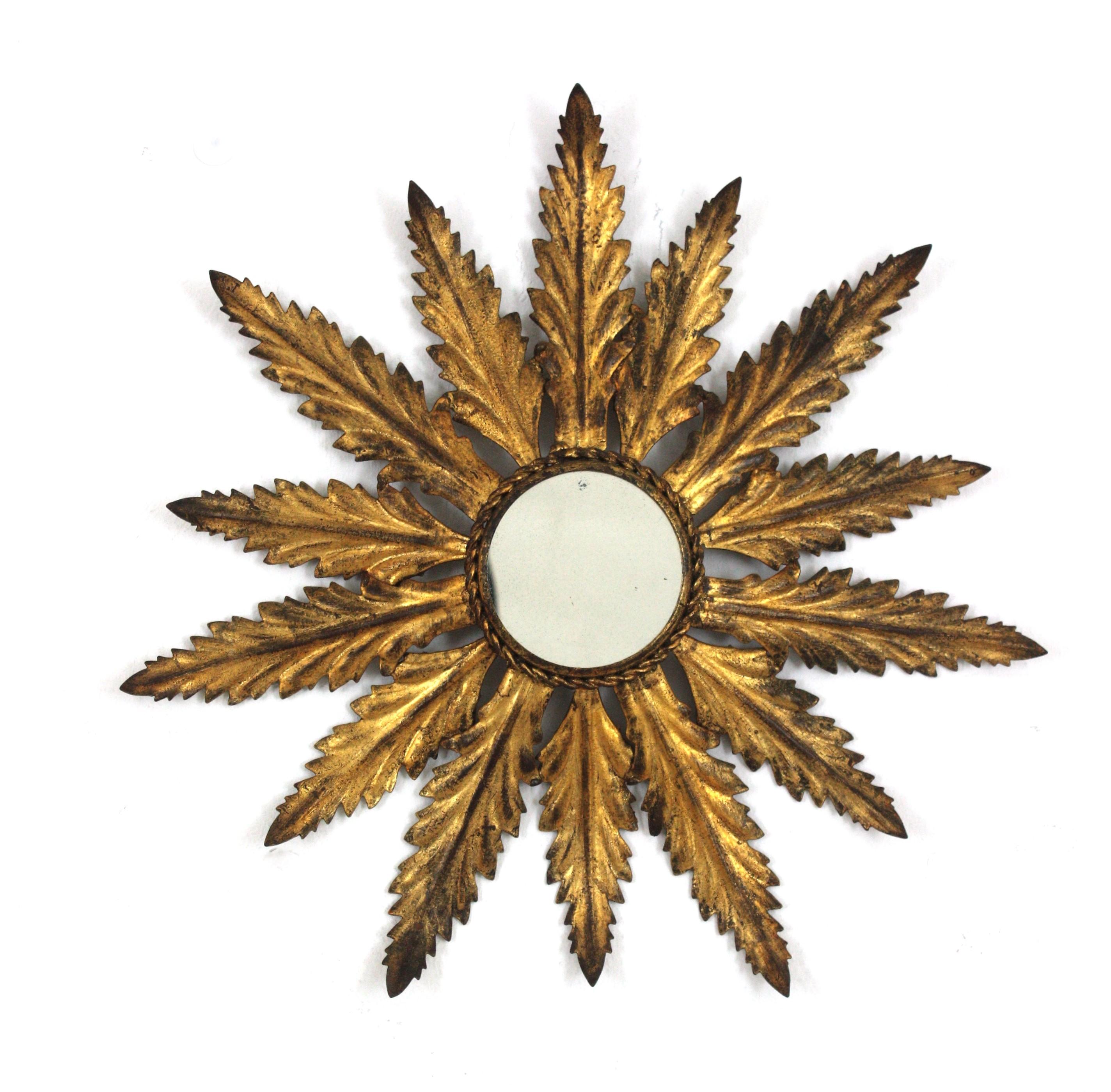 Small Sized Sunburst Mirror with Foliage Frame, Gilt Iron, Gold Leaf
Eye-catching hand-hammered gilt iron leafed sunburst mirror in small scale, Spain, 1940s-1950s.
The leafed frame in gilt iron is finished with gold leaf and retains a terrific aged