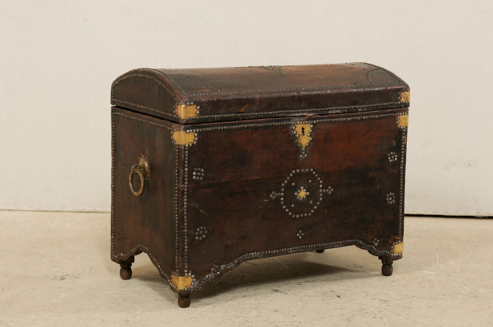 A Spanish leather wrapped wood trunk with brass and nail-head accents from the 19th century. This antique coffer from Spain has a rectangular-shape with domed top. The body and top are decorated with studs, creating floral and star shapes, and a