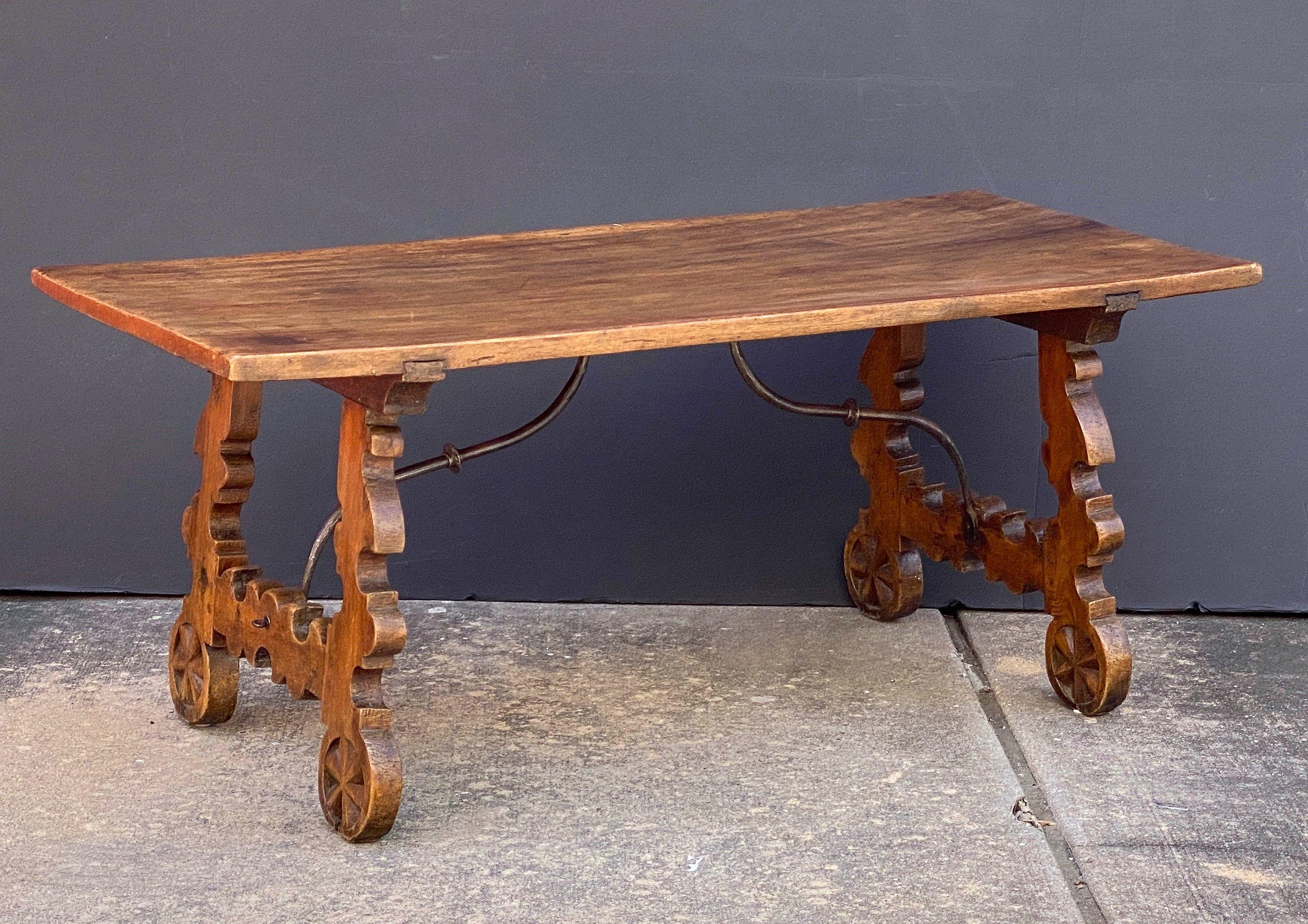 Belle table basse ou à tréteaux espagnole en noyer vieilli de la fin du XVIIIe siècle, présentant un plateau rectangulaire sur une frise de deux supports en bois tourné avec des entretoises en fer forgé dans un motif de barres transversales.

Avec