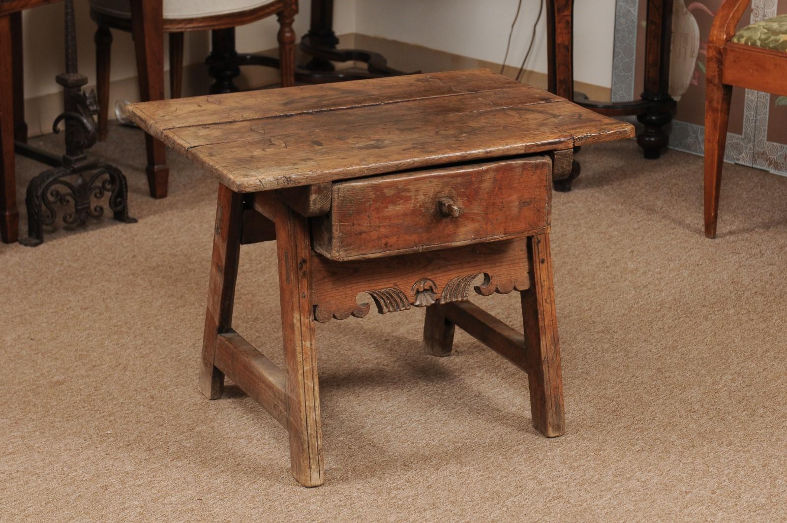 A Spanish low drink table in pine rectangular top, drawer below with wooden pull and carved apron.