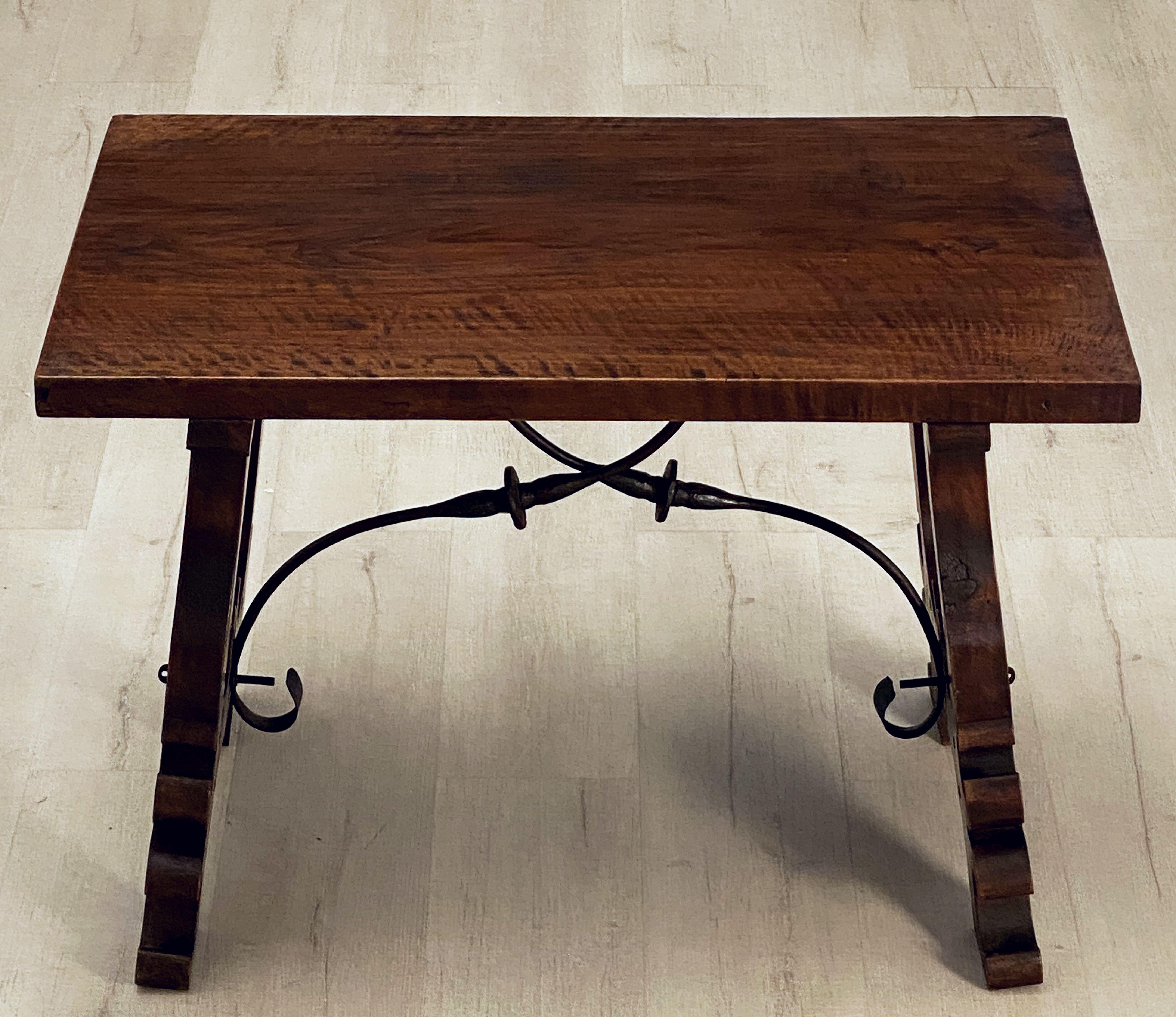 A handsome Spanish low table of walnut featuring a rectangular plank top over turned wood supports with wrought ironwork braces in a cross-bar design.

Functions as a great side table or coffee table as well.