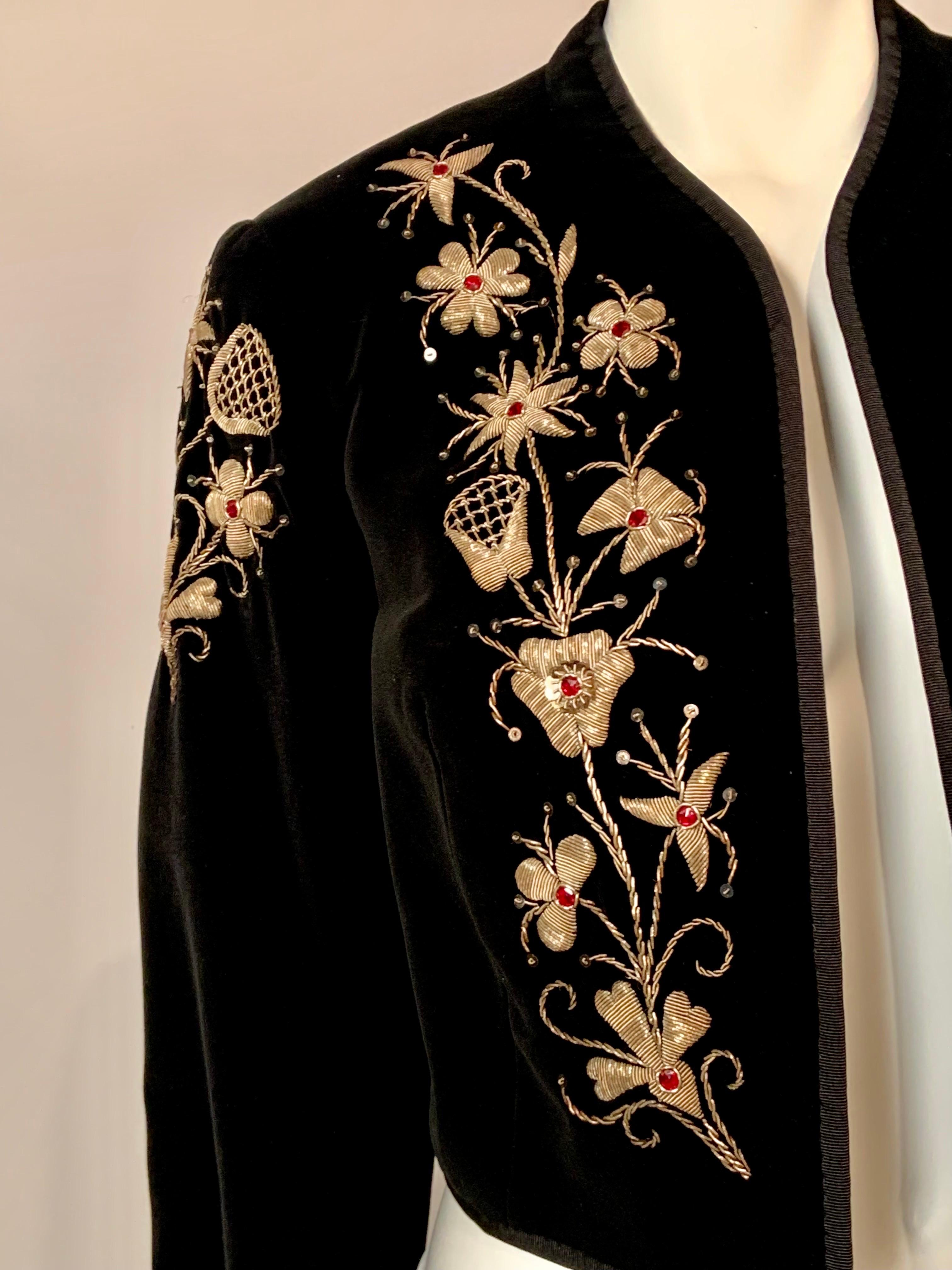 This black velvet bolero jacket was made in Madrid, circa 1970 and the right front side of 
the jacket has a large floral design embroidered in gold thread with red beads at the center of the flowers.  This embroidered design is repeated at the top