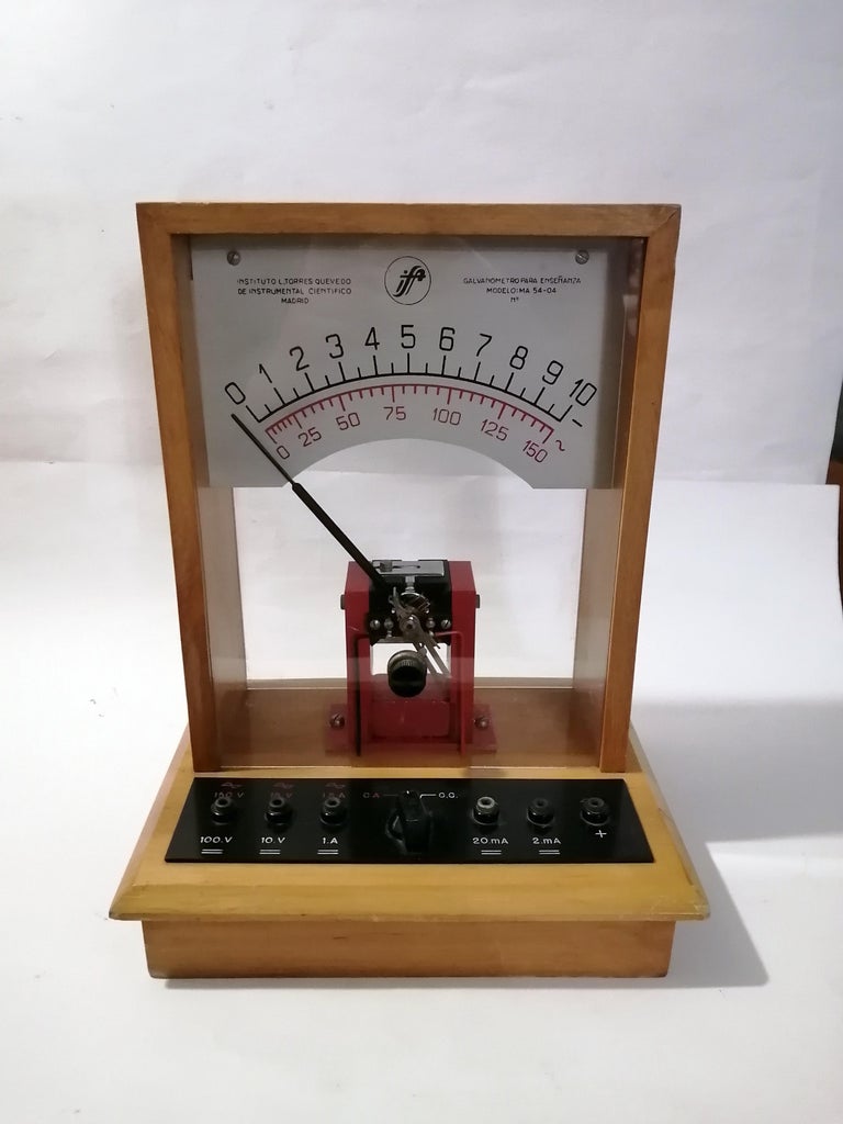 A 1950s Spanish Mid-Century Modern educational D'Arsonval galvanometer manufactured by the Leonardo Torres Quevedo Institute in Madrid. Model MA 54-04. The wood and glass structure stores a panel on front to connect cables. The galvanometer is