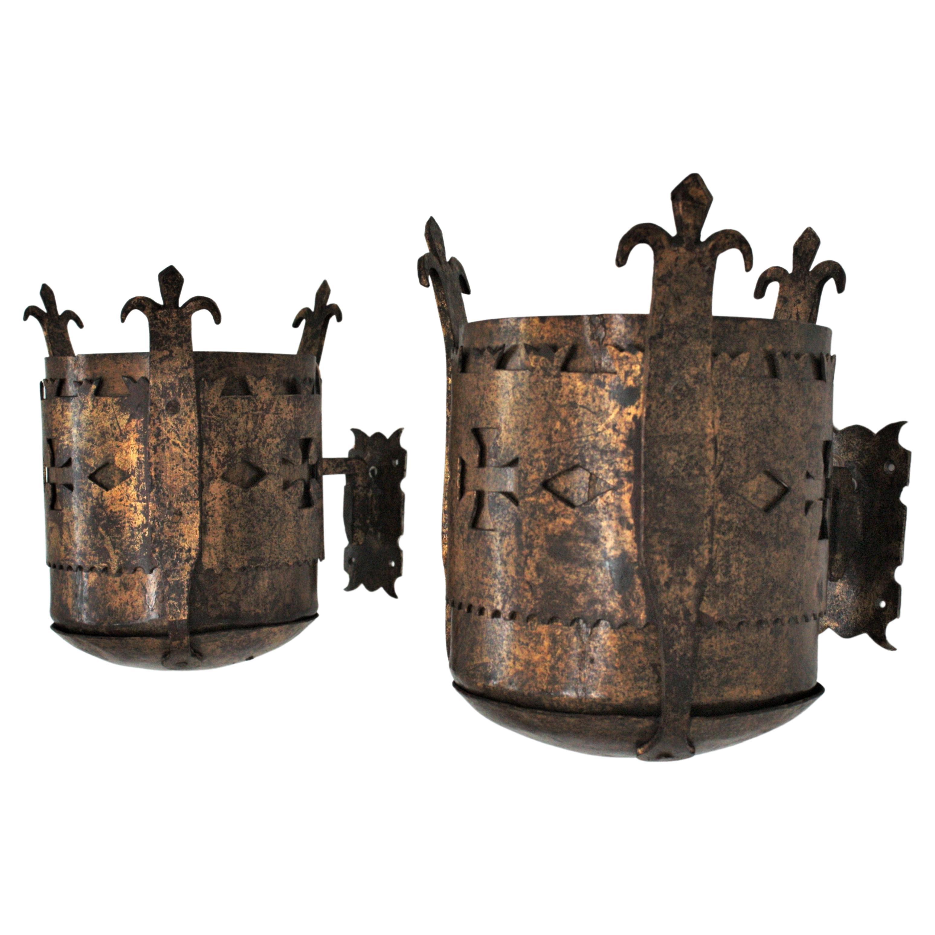 Spanish Medieval style hand forged uplighter torch wall sconces, 1930s.
Rare hand forged iron gothic inspired cylinder wall lights with terrific aged patina showing the original gold leaf gilding.
This pair of medieval iron sconces are all made by