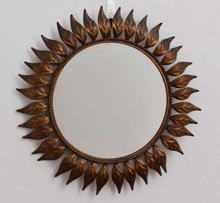 Spanish tôle sunburst mirror in copper patina (c. 1960s) with leaf motif rays and rope-pattern mirror border. In fair-to-good overall condition. Some minor age-related blemishes appear on the mirror glass reflecting (excuse the pun) its true age and