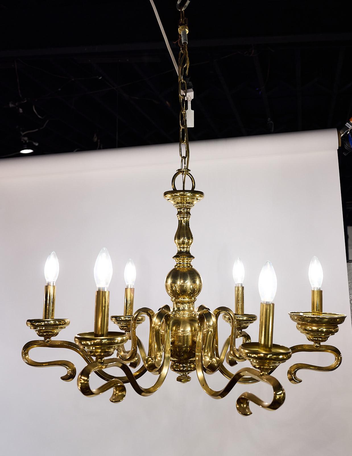 Spanish chandelier of brass having six arms that are traditional in overall form yet wonderfully baroque in style. Marked ‘Made in Spain’.  Circa 1950s. 

The chandelier measures 29” in diameter x 19” in height; the existing chain provides a 16”