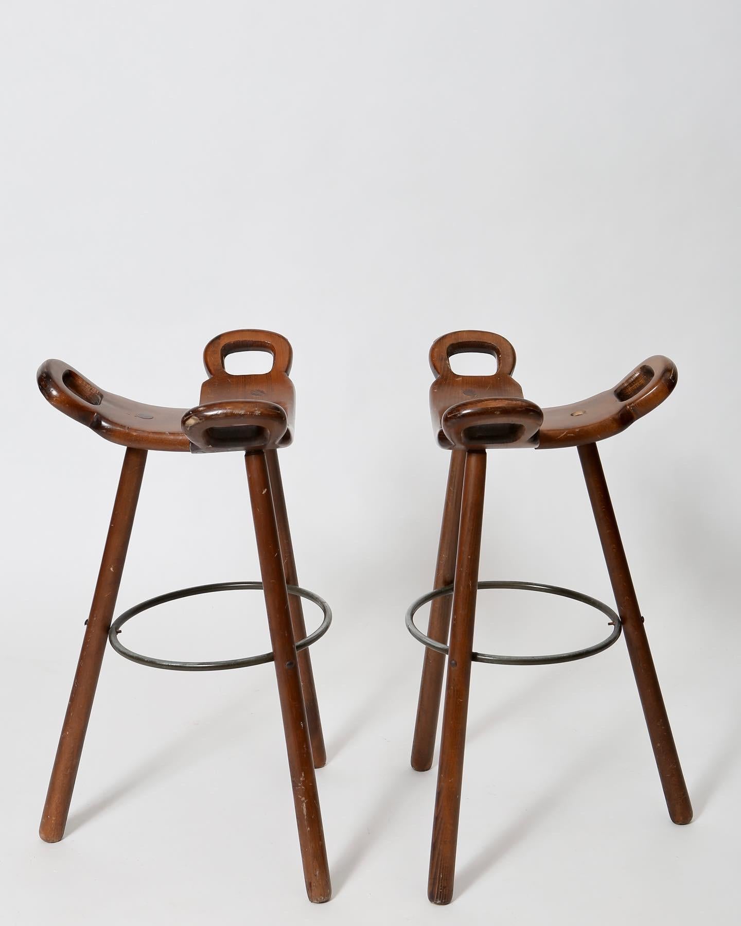 Pair stained beech barstools made in Spain, circa 1960s. Steel and wood. Charming folk brutalist styling. Comfortable and sculptural, with original finish and plenty of character. Standard bar height with seats at 30”.