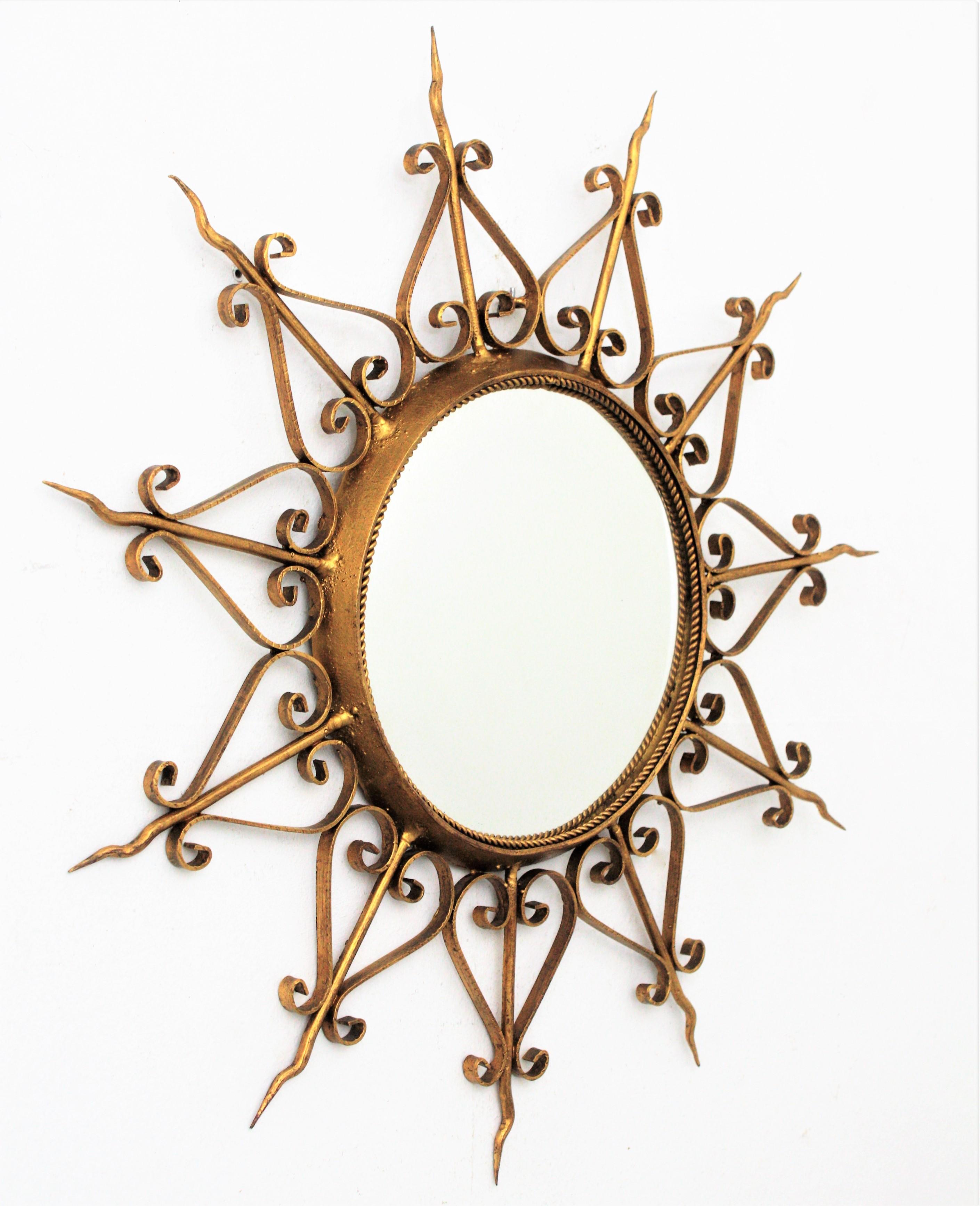 Hand-hammered gilt iron sunburst mirror with ornamented frame and convex glass. Spain, 1950s.
This highly decorative mirror shows a beautiful gilt aged patina and scroll motifs adorning the rays. Interesting to be placed alone or with other