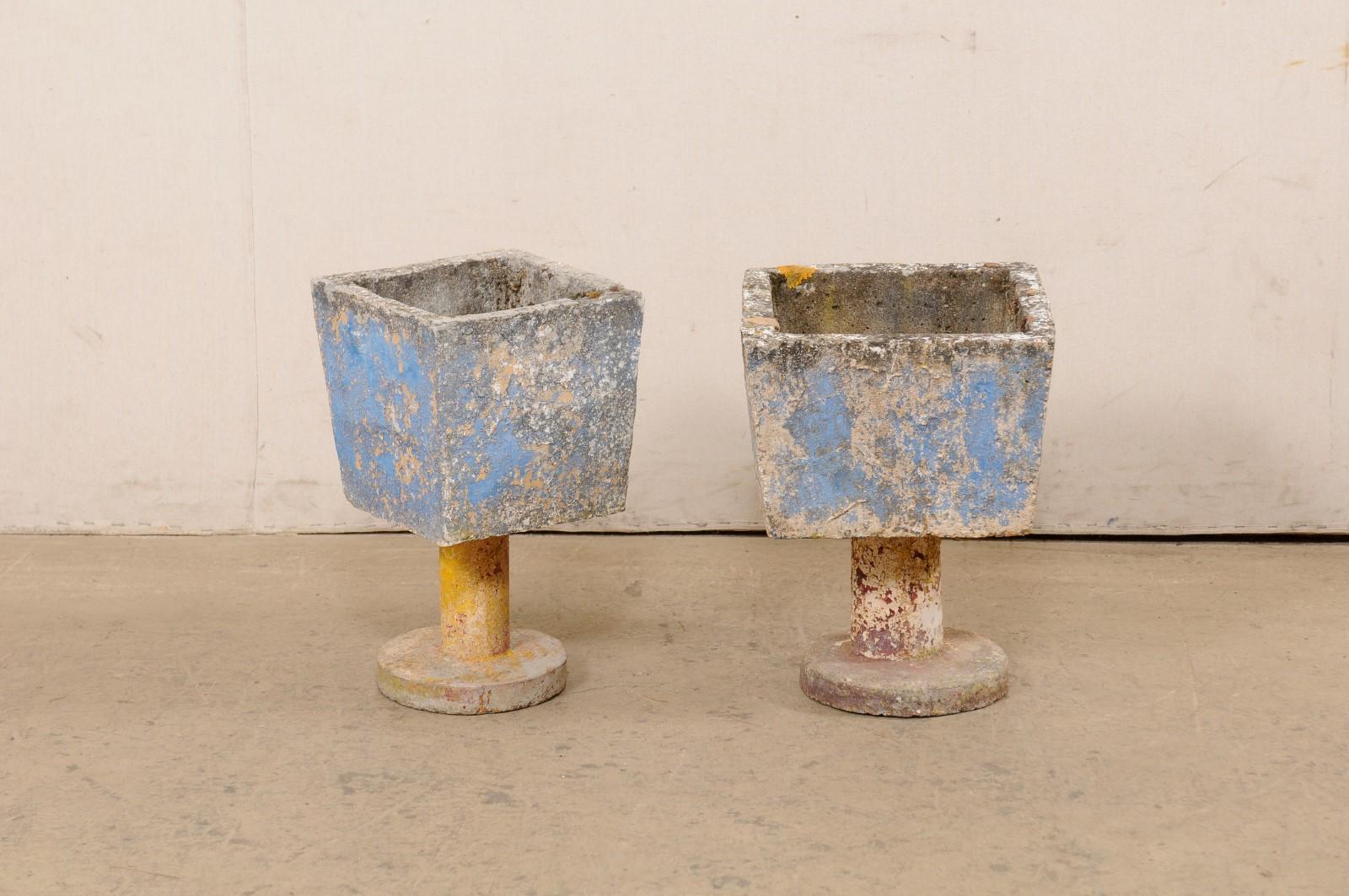 A Spanish near-pair of cast-stone planters, with their original paint, from the mid-20th century. These playful garden planters from Spain have square-shape bodies which are raised on cylindrical pedestals, and supported on a round platform base.
