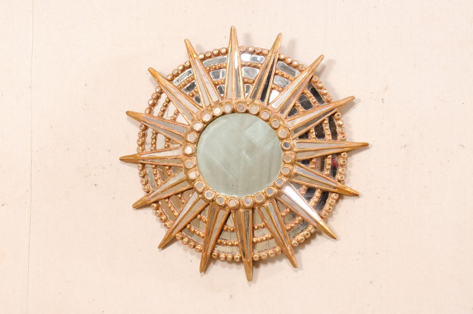 A Spanish round-shaped mirror with large sun motif at center, from the mid 20th century. This mid-century wall decoration from Spain features a sun-shaped design with a round glass/mirror at its center, framed within a series of stacked/ circular