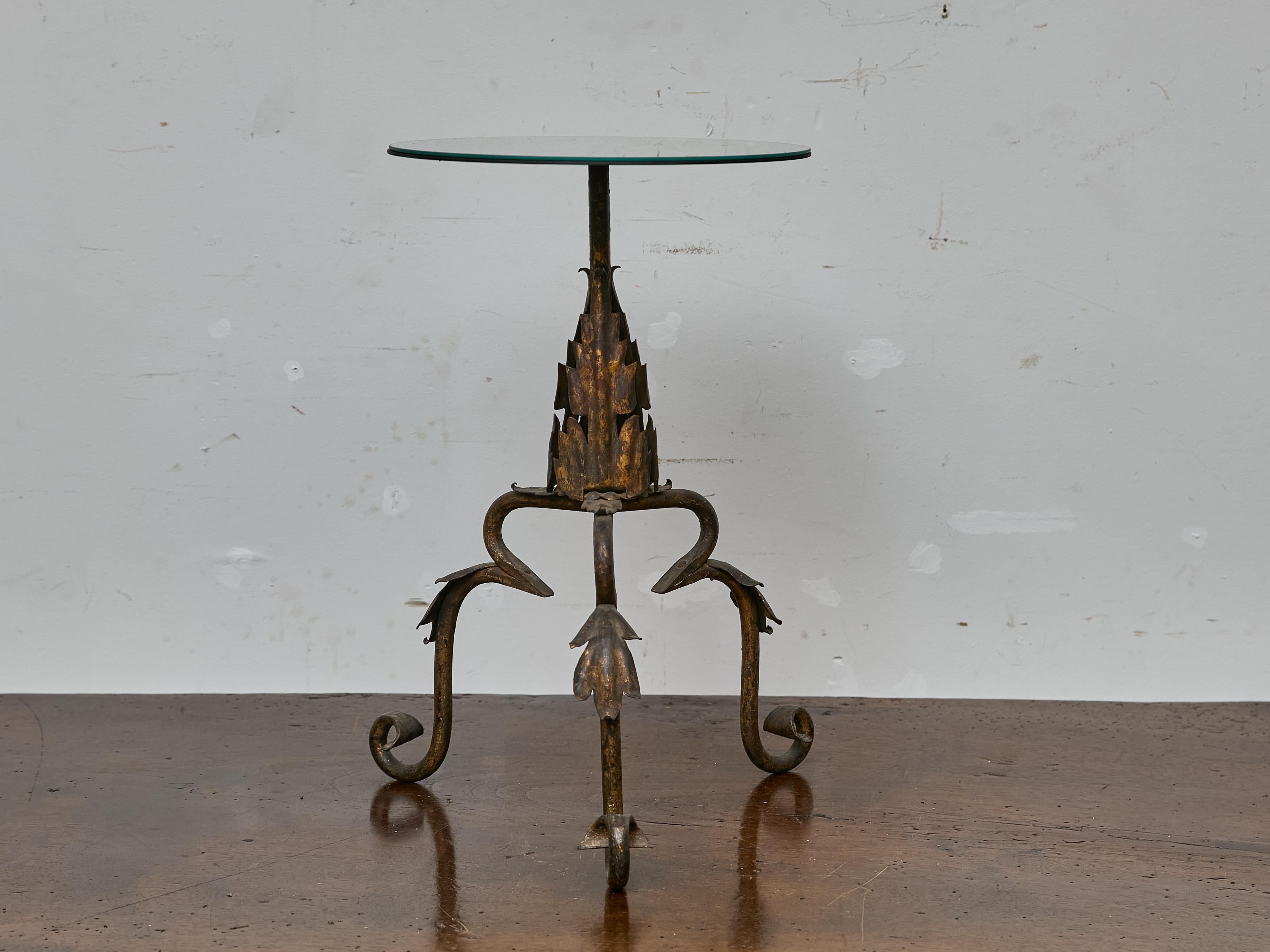 A charming and sculptural midcentury iron table from Spain, this petite piece blends wrought craftsmanship with a hint of organic fantasy. Standing at 22 inches high with a 13.5-inch diameter top, the table is scaled for use as an occasional piece —