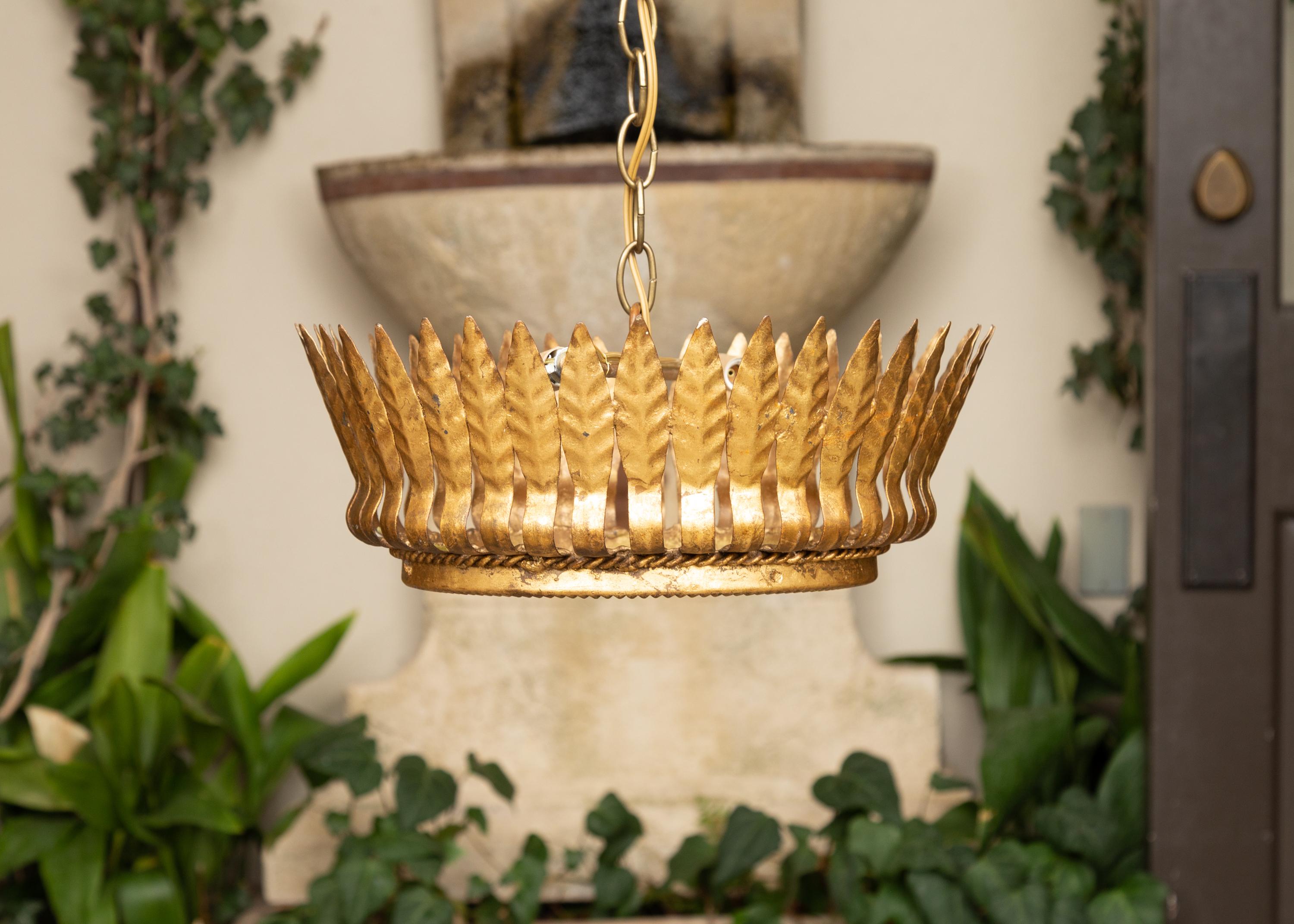 A Spanish gilt metal crown semi-flush chandelier from the mid-20th century with leaf motifs, two bulbs and frosted glass. Crafted in Spain during the midcentury period, this Spanish gilt metal chandelier is adorned with leaf motifs all the way