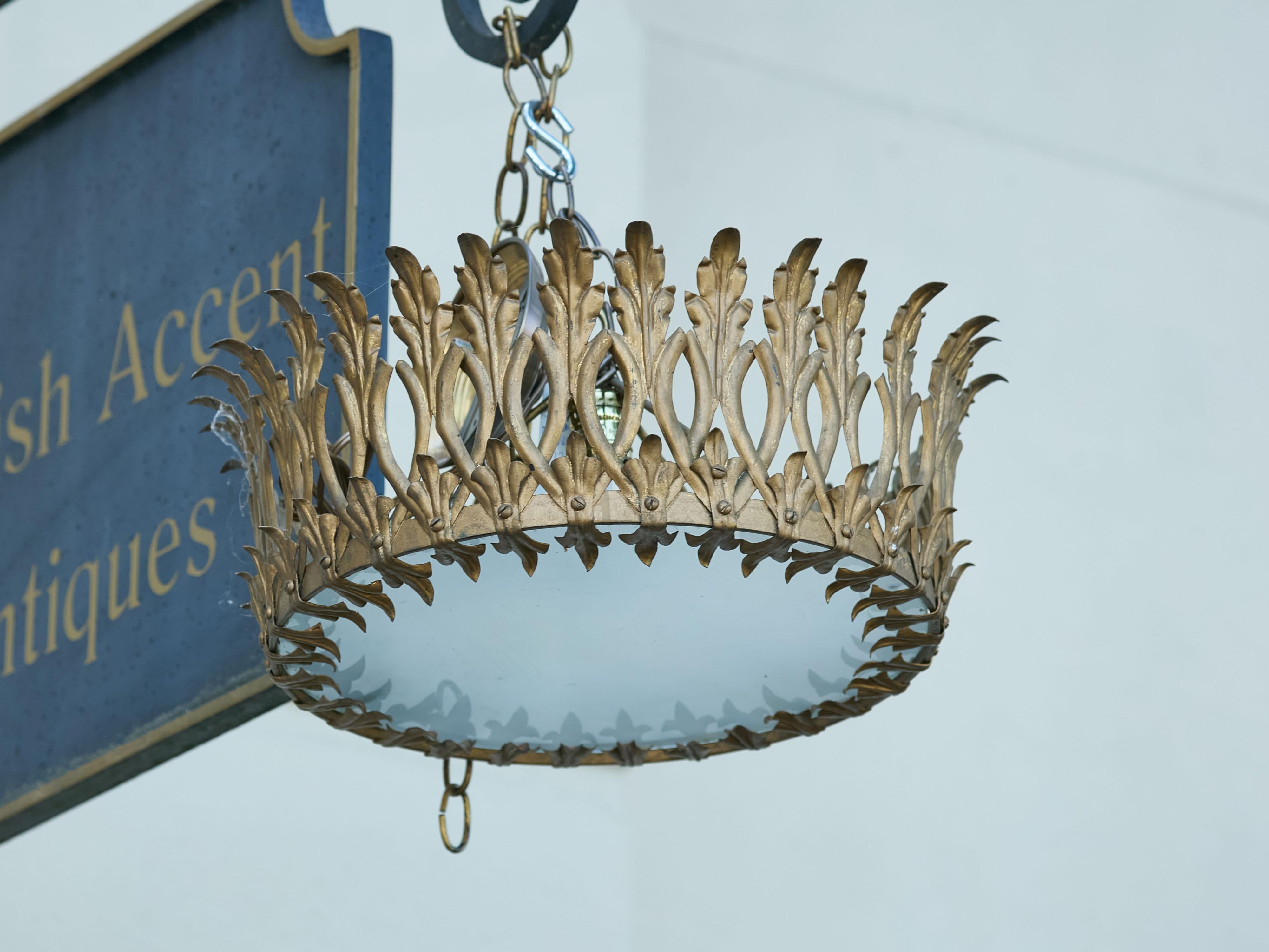 A Spanish gilt metal crown chandelier from the Midcentury period, with elongated leaves and frosted glass bottom. Created in Spain during the midcentury period, this gilt metal crown chandelier exudes timeless elegance and refined craftsmanship. The