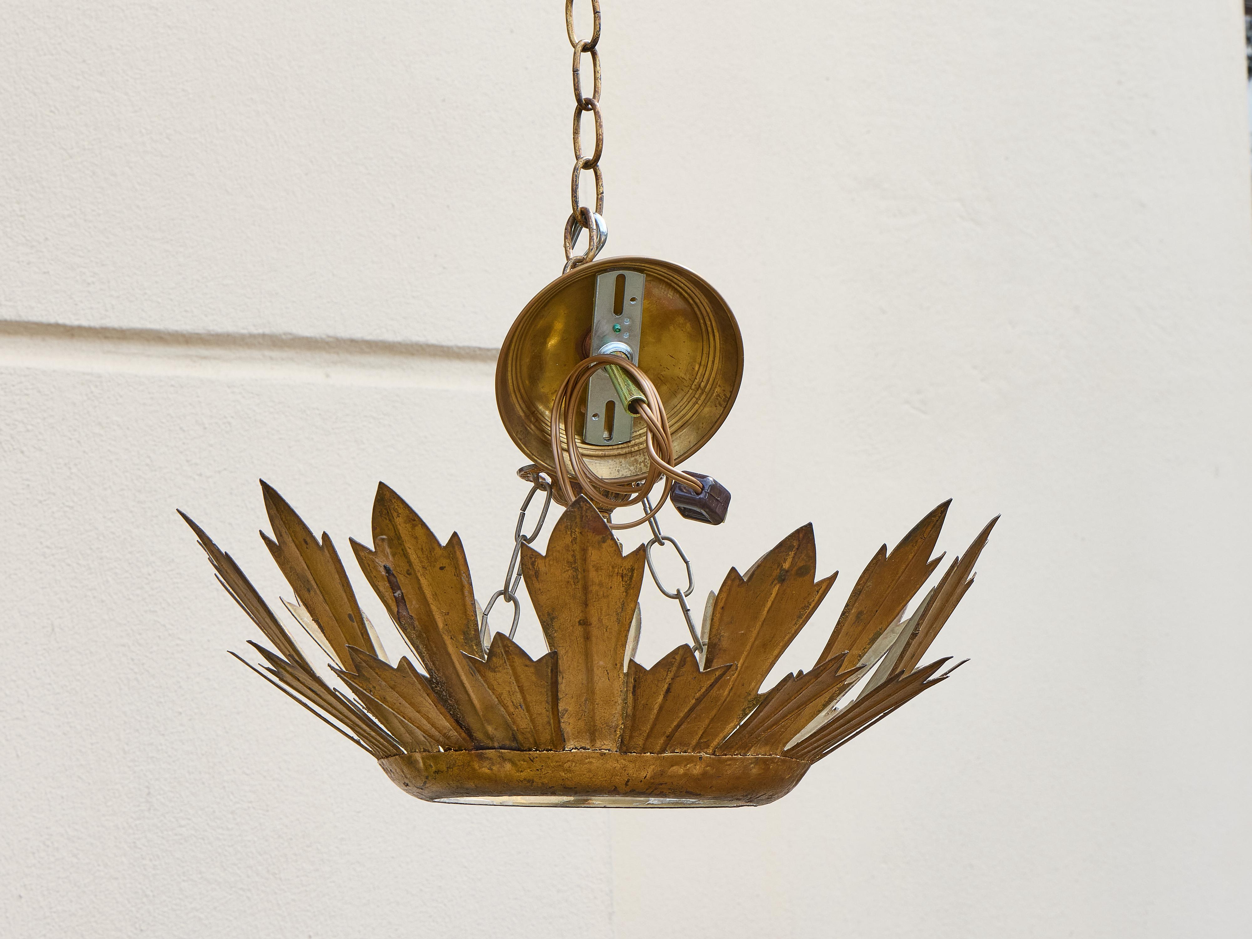 Cette suspension espagnole en métal doré du milieu du siècle, datant d'environ 1950, présente une étonnante silhouette en forme de couronne composée de formes feuillues découpées à la main qui évoquent un feuillage stylisé. Le motif botanique ajoute