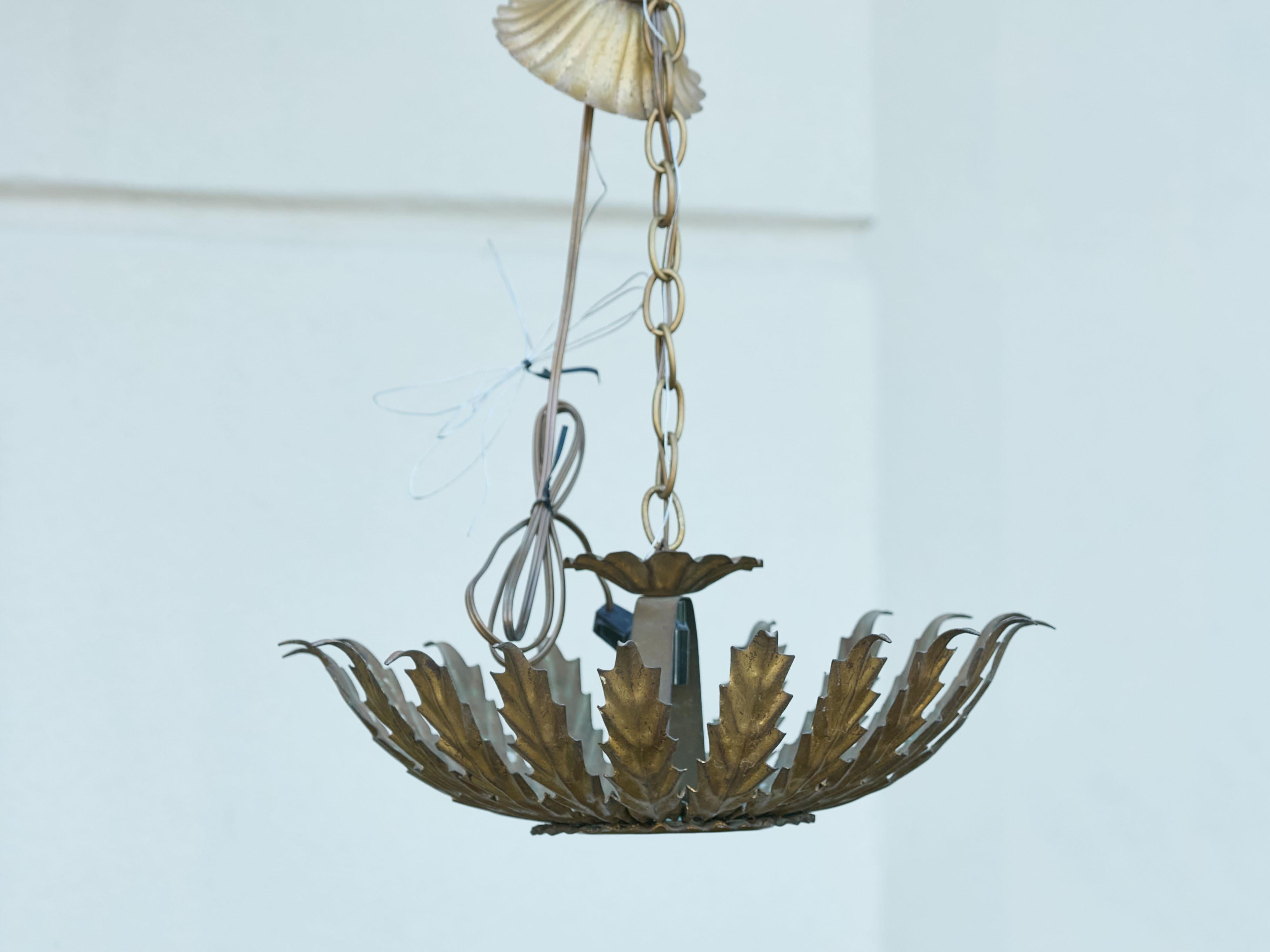 A Midcentury Spanish gilt metal single-light sunburst crown chandelier, with curving leaves and frosted glass, US wired. Created in Spain during the midcentury period, this gilt metal sunburst crown chandelier captivates with its radiant design and