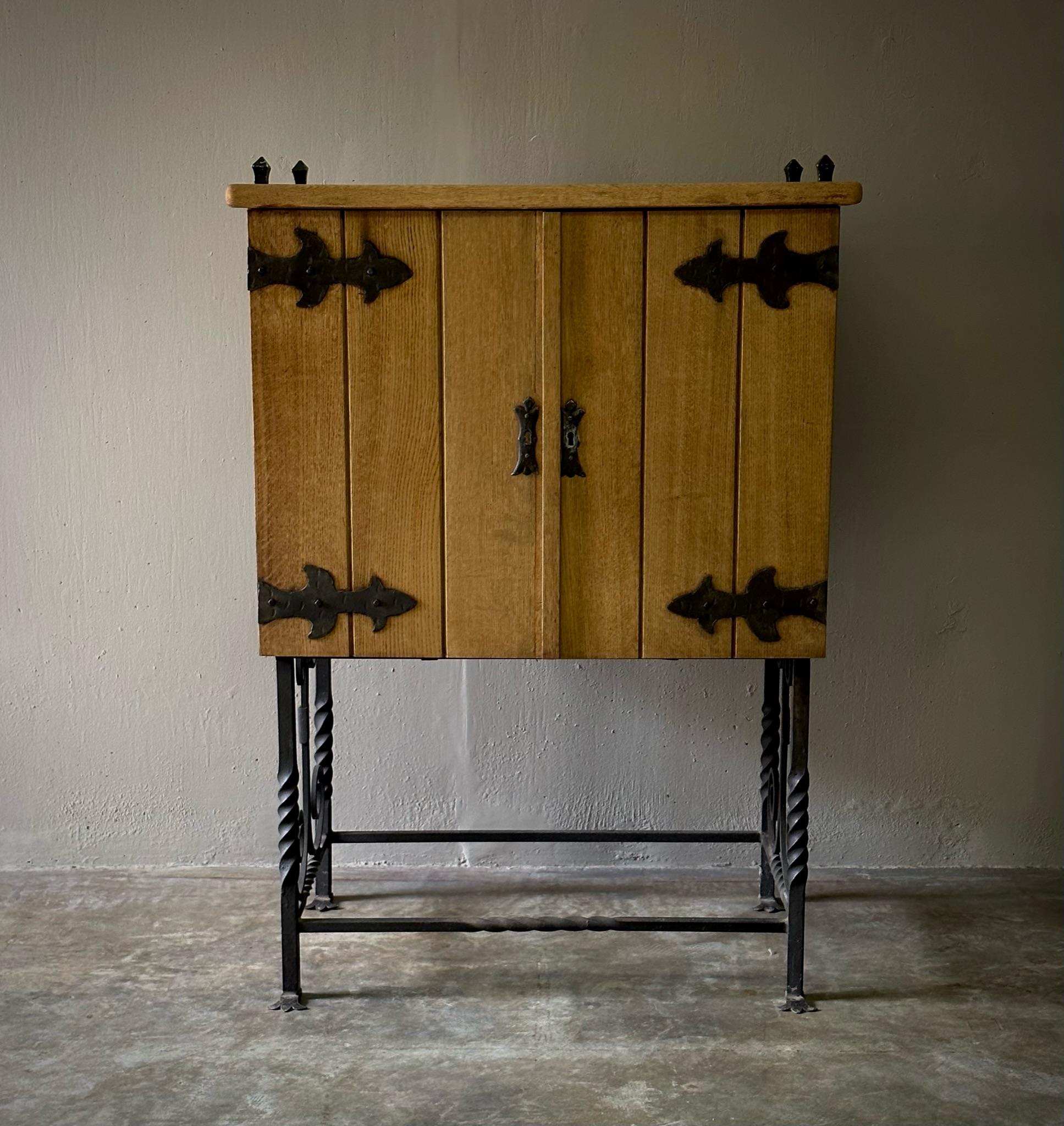 Spanish mid-century drinks cabinet with floriated wrought iron handles and decorative accents and tawny blonde slat wood siding, typical of the traditional Spanish-style pieces of this period.

Spain, circa 1960

Dimensions: 36 W x 21 D x 50 H.