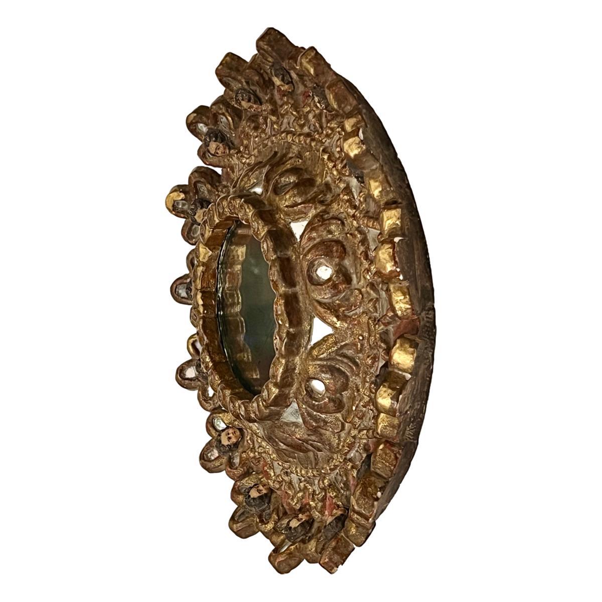 Miroir espagnol en bois doré des années 1920 avec des visages d'anges sur le cadre.

Mesures :
Diamètre : 19