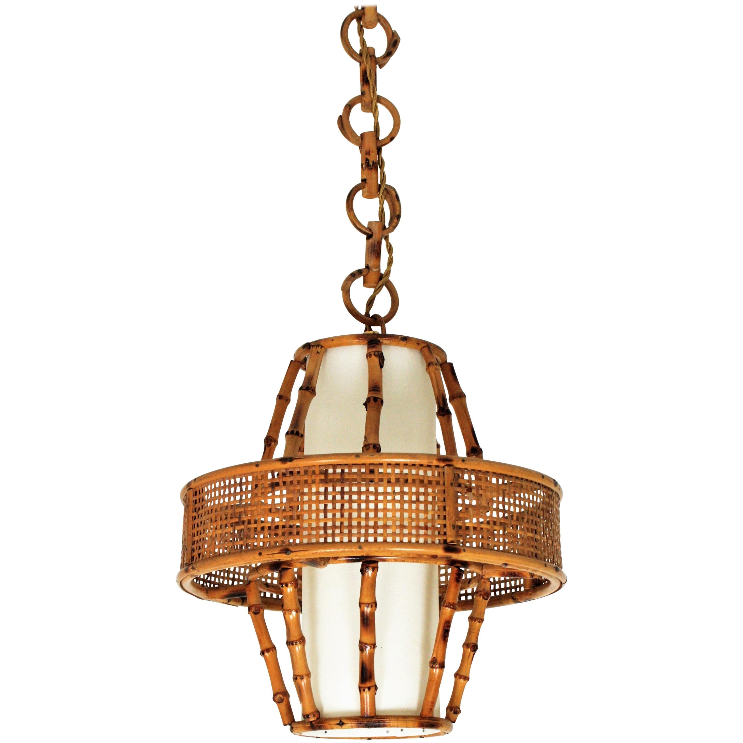 Spanish Mid-Century Modern bamboo and rattan hanging pendant lamp/ lantern with woven wicker accents and interior paper lampshade.
Manufactured at the Mid-Century Modern period with tiki or oriental accents, Spain, 1950s.
This sculptural lamp
