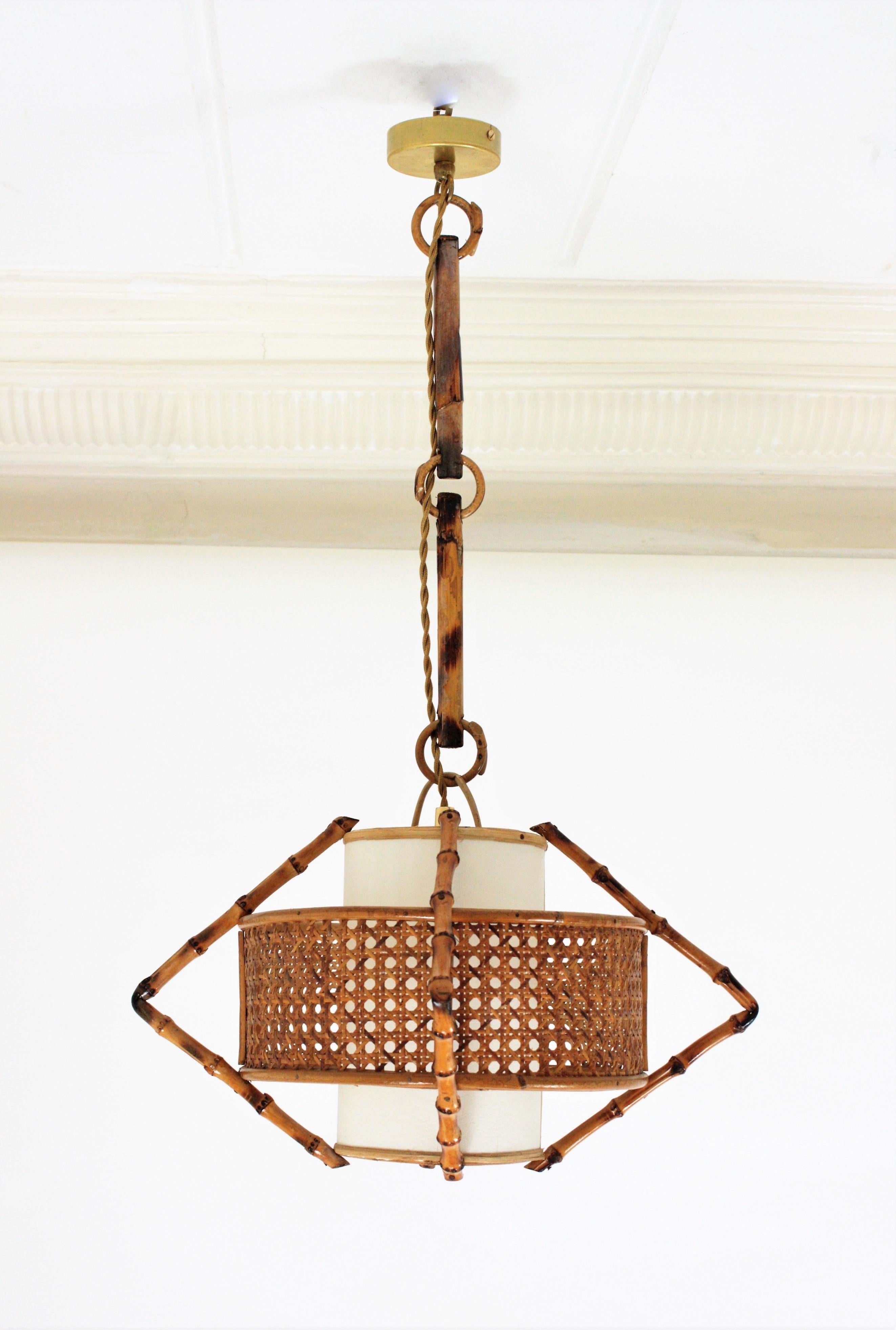 Unusual handcrafted bamboo and rattan hanging pendant lamp with a woven wicker shade. Manufactured at the Mid-Century Modern period with Tiki or oriental accents, Spain, 1950s.
This sculptural lamp combines a midcentury taste at the woven wicker