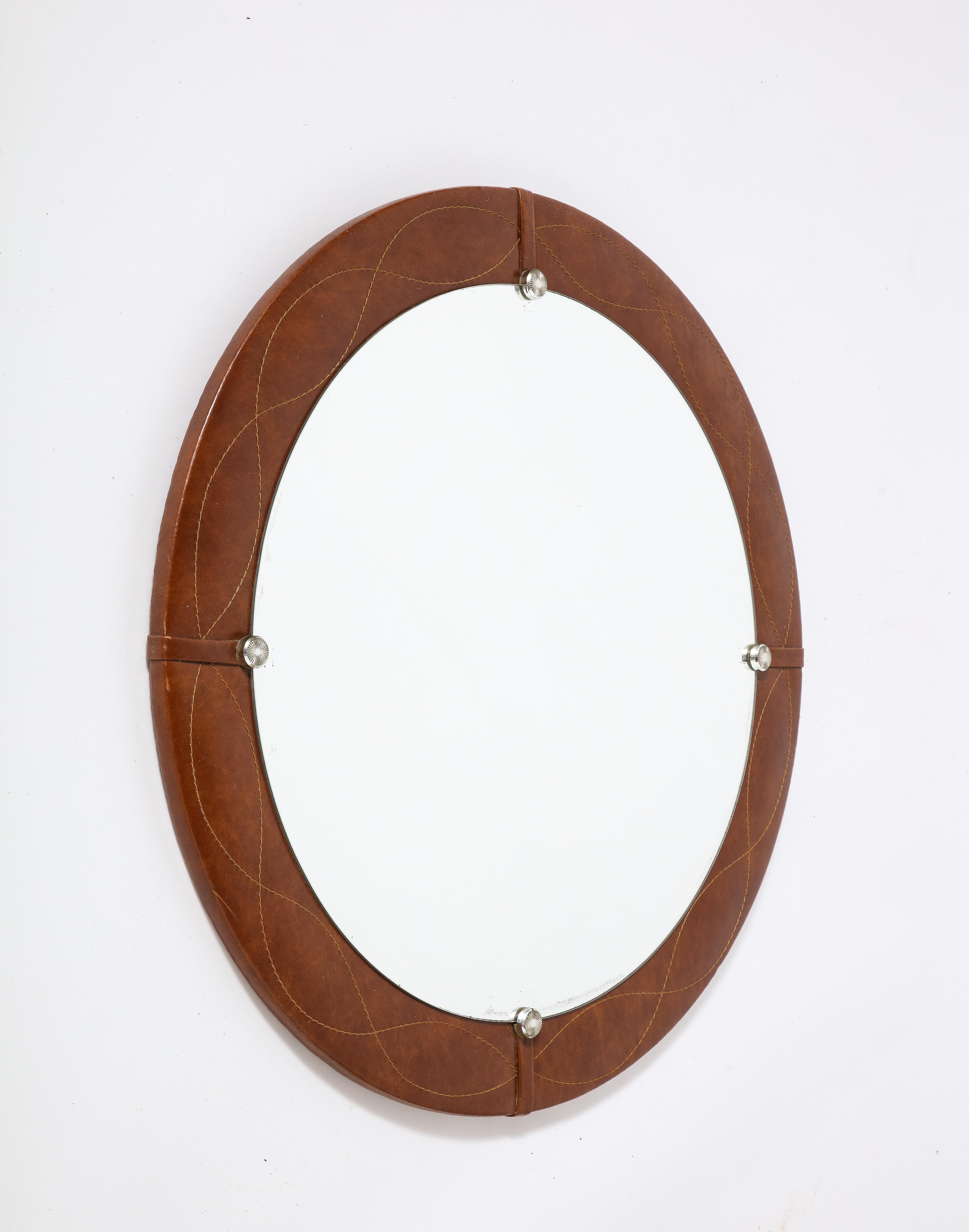 A wonderful and charming Spanish modernist circular mirror wrapped in leather with scroll stitching and chrome rosettes. 
Spain, circa 1960 
Size: 27