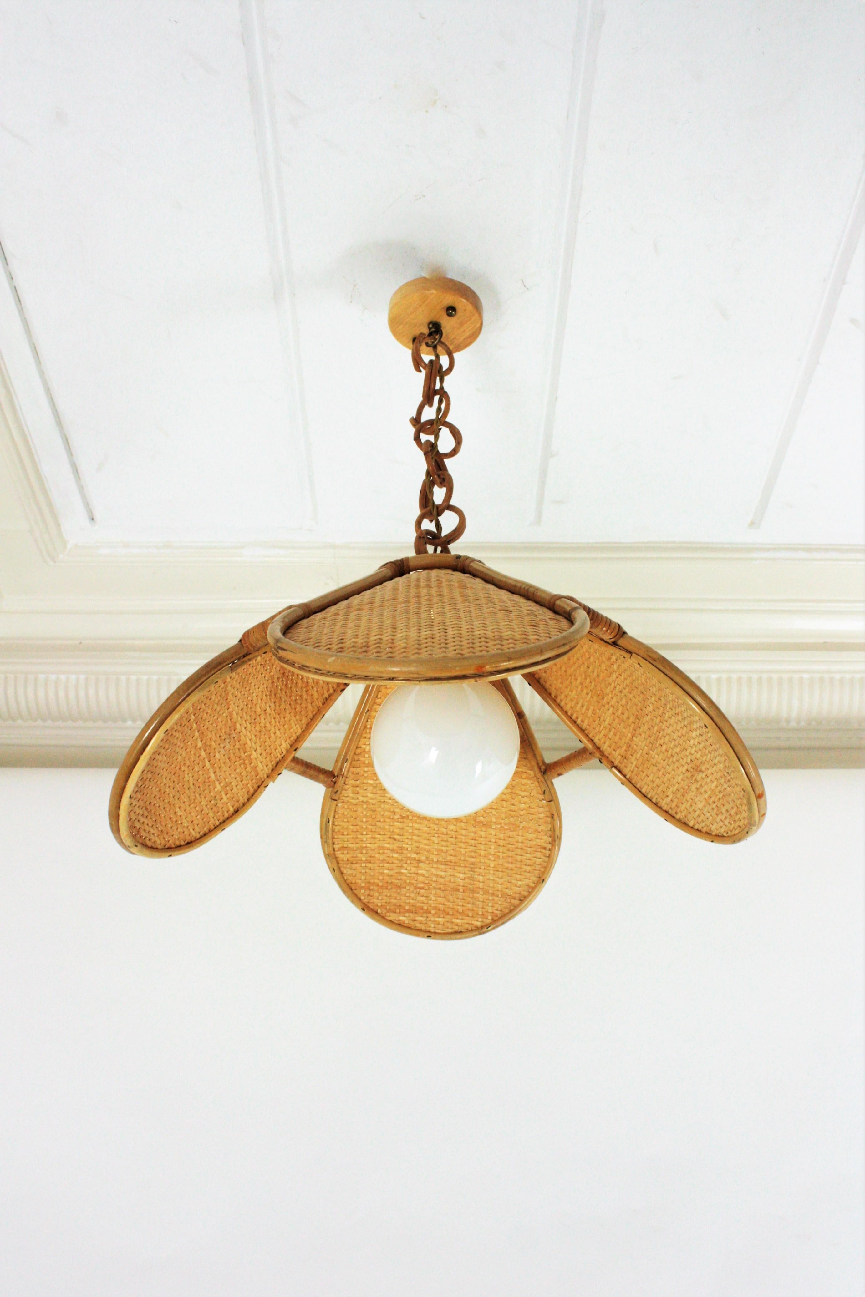 Elegant handcrafted bamboo and rattan or wicker weave flower shaped or palm pendant hanging lamp, Spain, 1960s.
This beautiful suspension lamp features a palm shaped bamboo lampshade structure with woven wicker panels. It hangs from a chain with