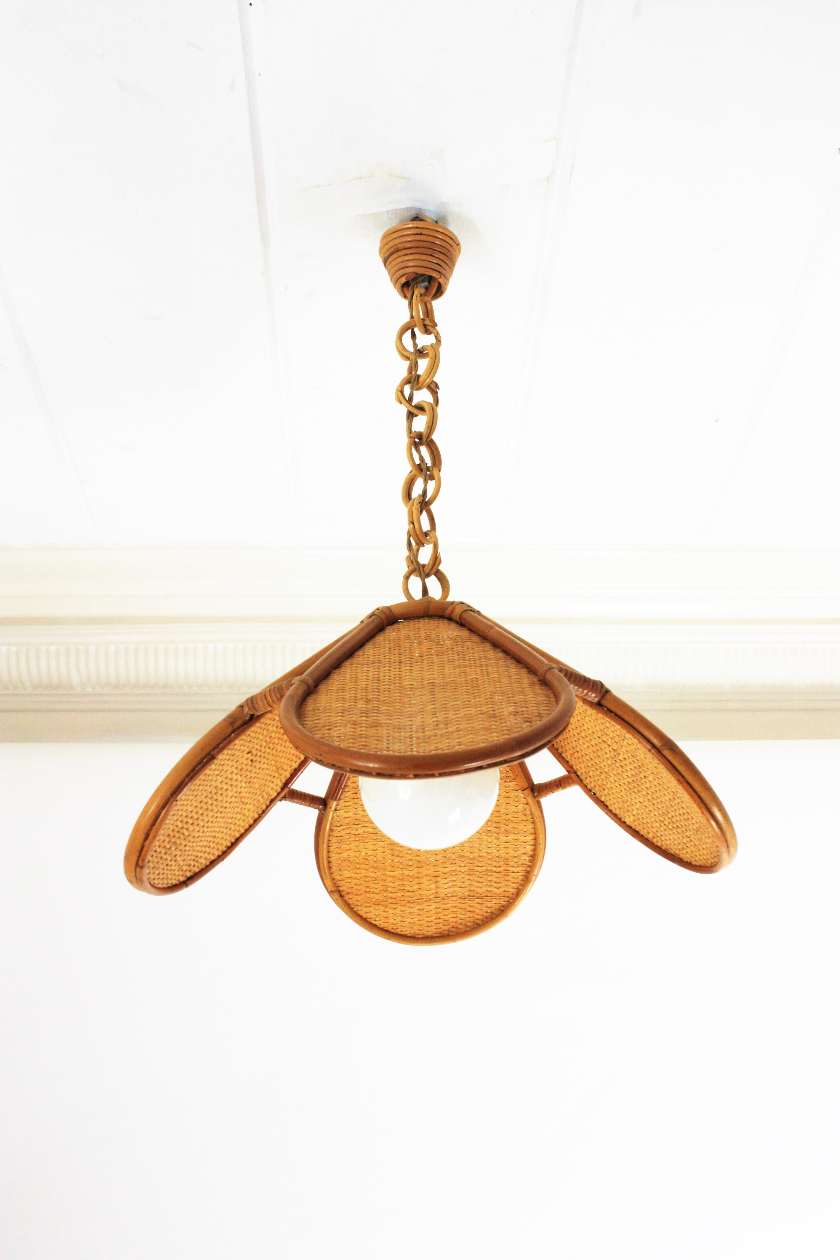 Elegant handcrafted bamboo and rattan or wicker weave flower shaped or palm pendant hanging lamp, Spain, 1960s.
This beautiful suspension lamp features a palm shaped bamboo lampshade structure with woven wicker panels. It hangs from a chain with