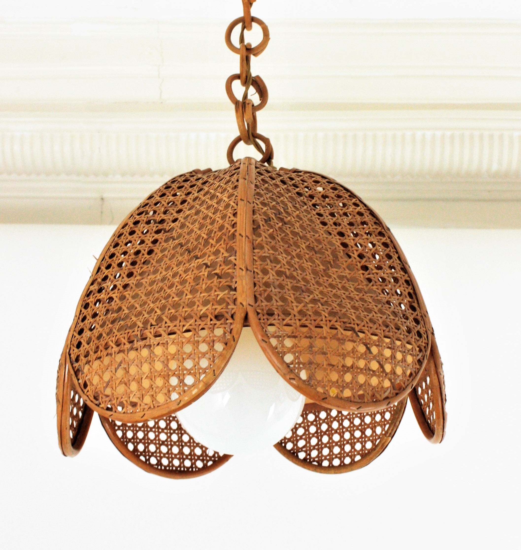 Elegant handcrafted bamboo and rattan / wicker weave flower shaped or palm pendant hanging lamp, Spain, 1960s.
This beautiful suspension lamp features aflower shaped rattan lampshade structure with woven wicker wire panels. It has a inner conical
