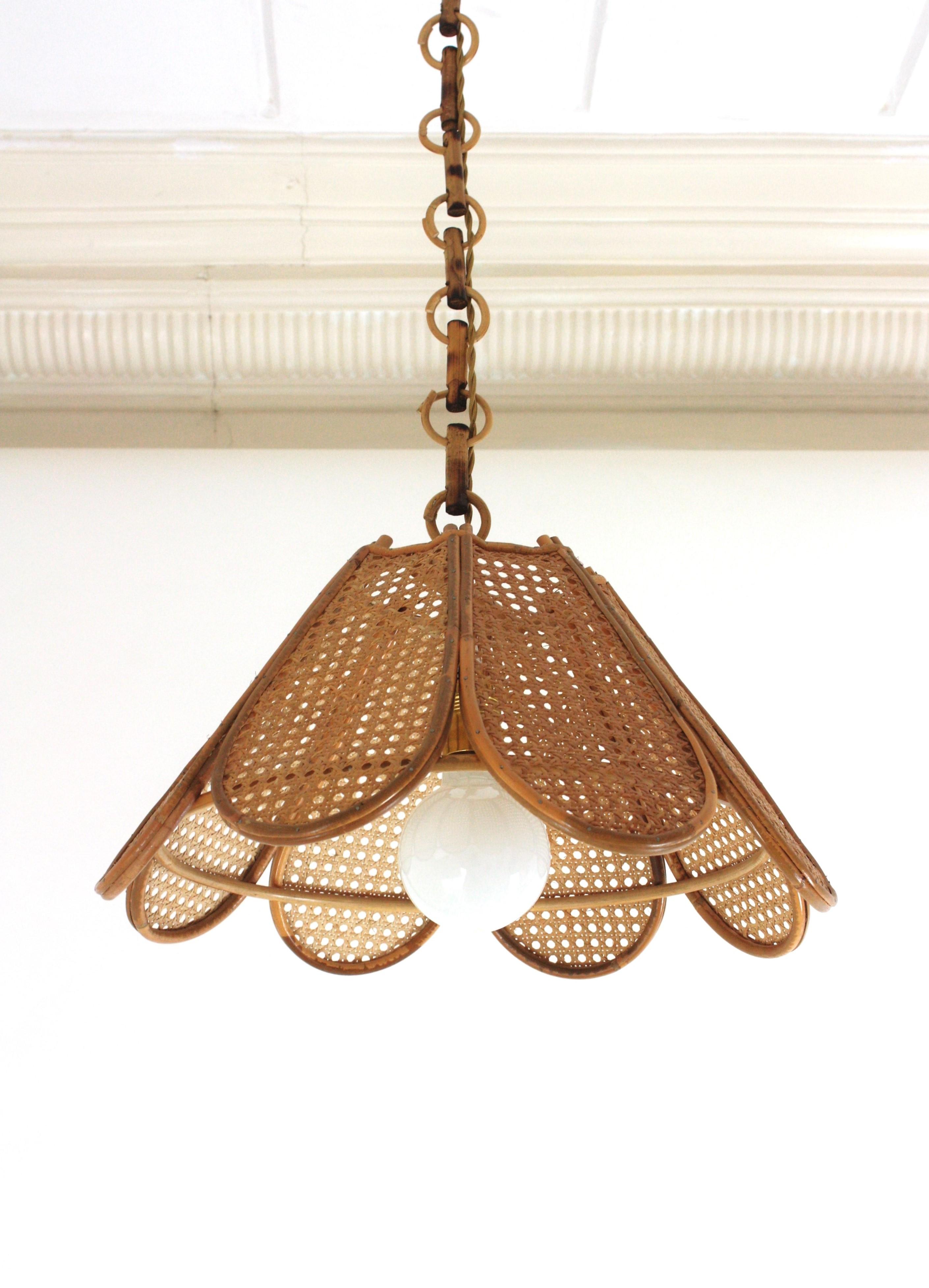 Elegant handcrafted bamboo and rattan / wicker weave flower shaped or palm pendant hanging lamp, Spain, 1960s.
This beautiful suspension lamp features a palm shaped rattan lampshade structure with petals made of rattan bars and woven wicker wire