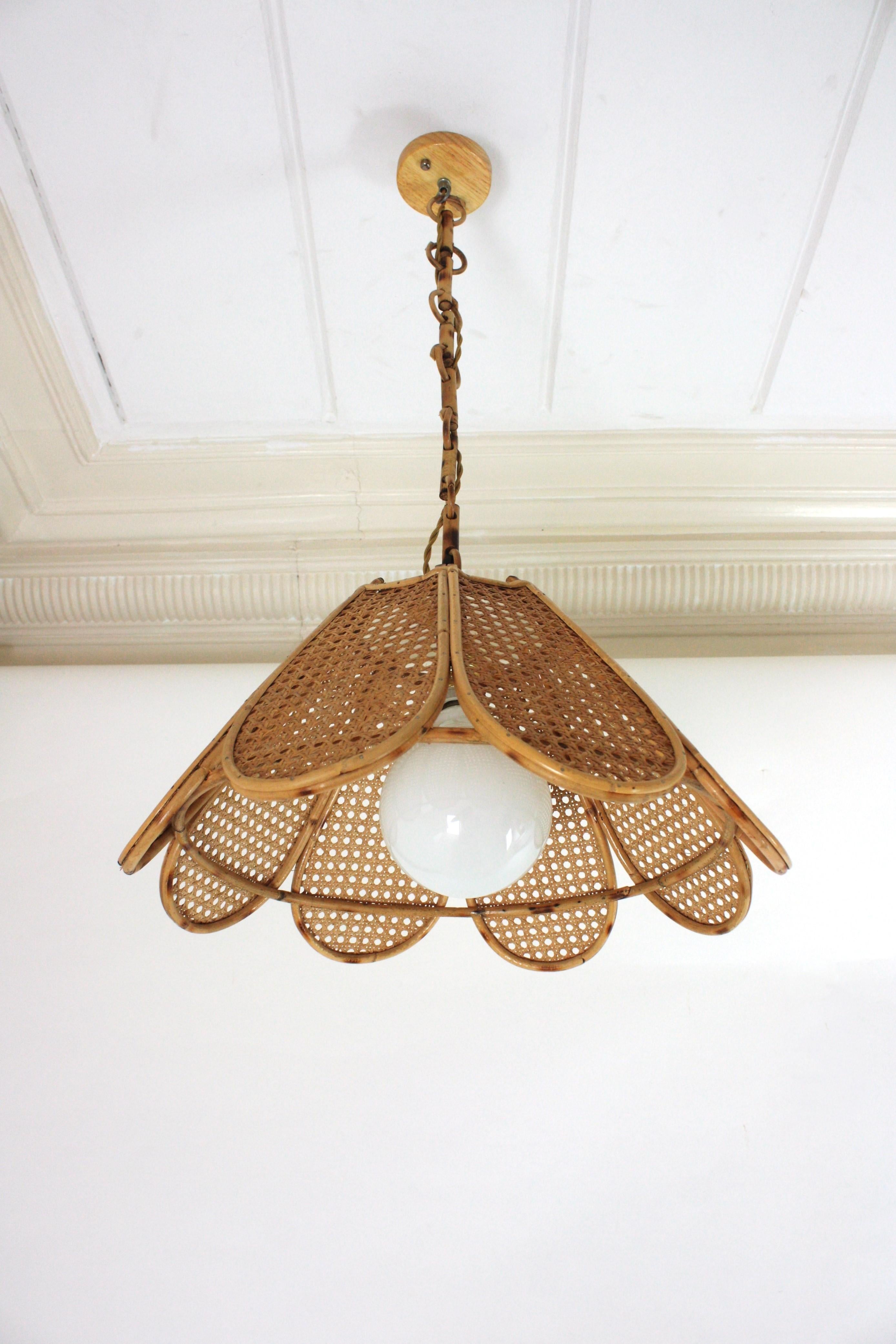 Elegant handcrafted bamboo and rattan / wicker weave flower shaped or palm pendant hanging lamp, Spain, 1960s.
This beautiful suspension lamp features a palm shaped rattan lampshade structure with petals made of rattan bars and woven wicker wire