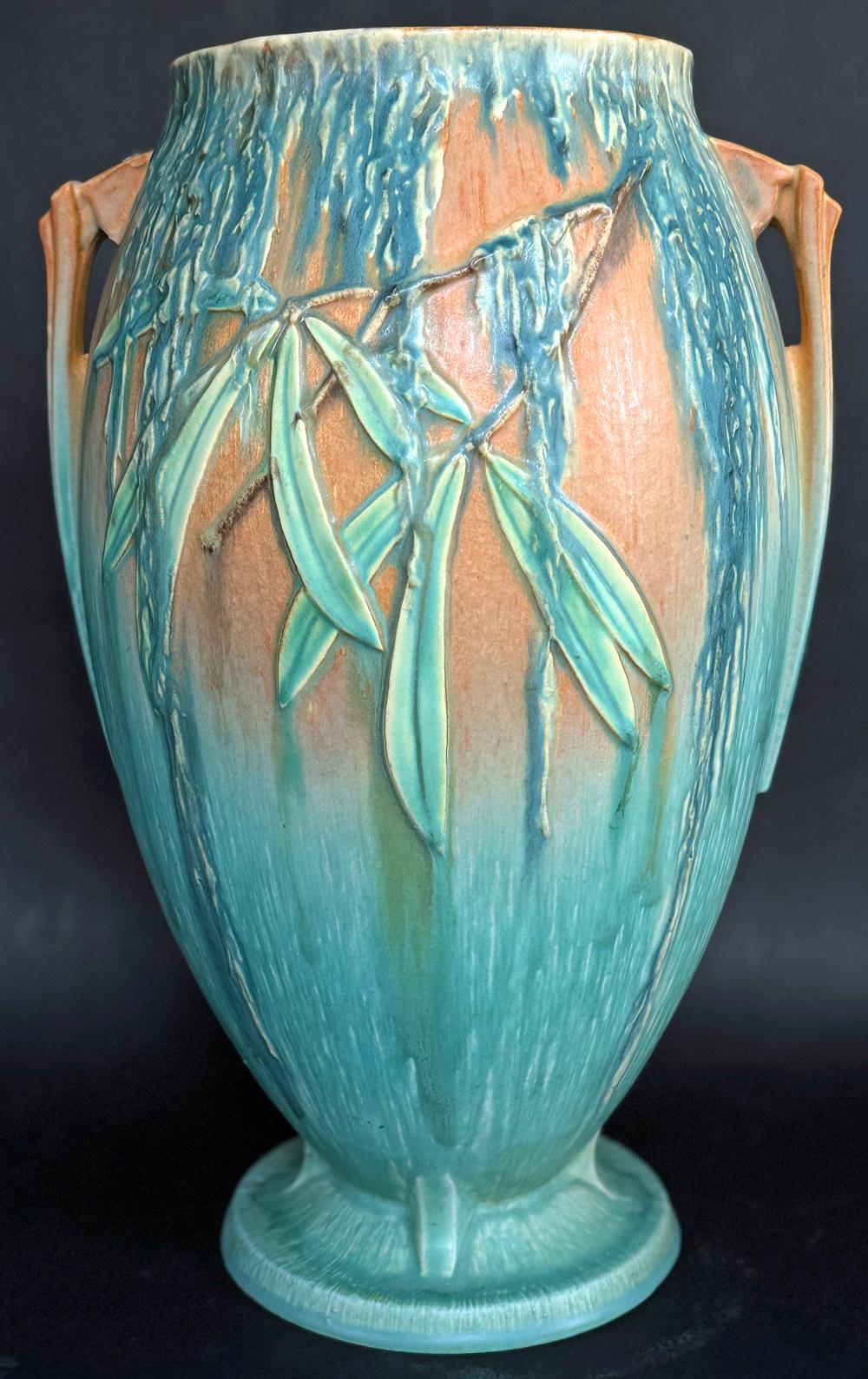 Unusual in size and hue, this large Art Deco vase features cascades of Spanish moss in tones of blue green over a ground the color of pumpkin, all on a swelling form with stylized handles.  The moss line was created in the mid-1930s by Frank