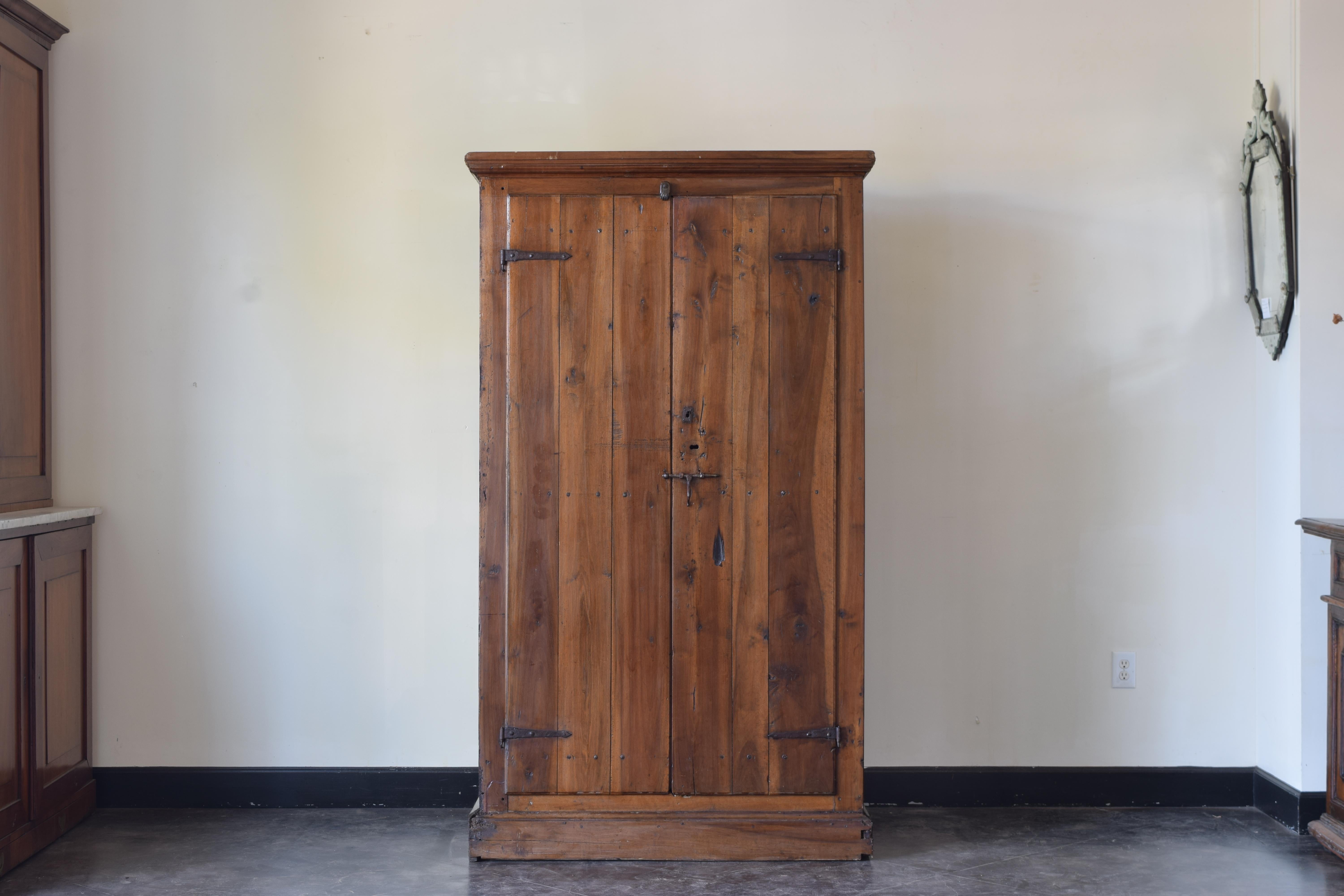 Primitive armadio or cabinet with a molded cornice and plinth-form base with two doors in hand-planed and wonderfully grained walnut with original hand forged irons bracing the doors to the shallow body.  Having one sliding iron lock/pull and the