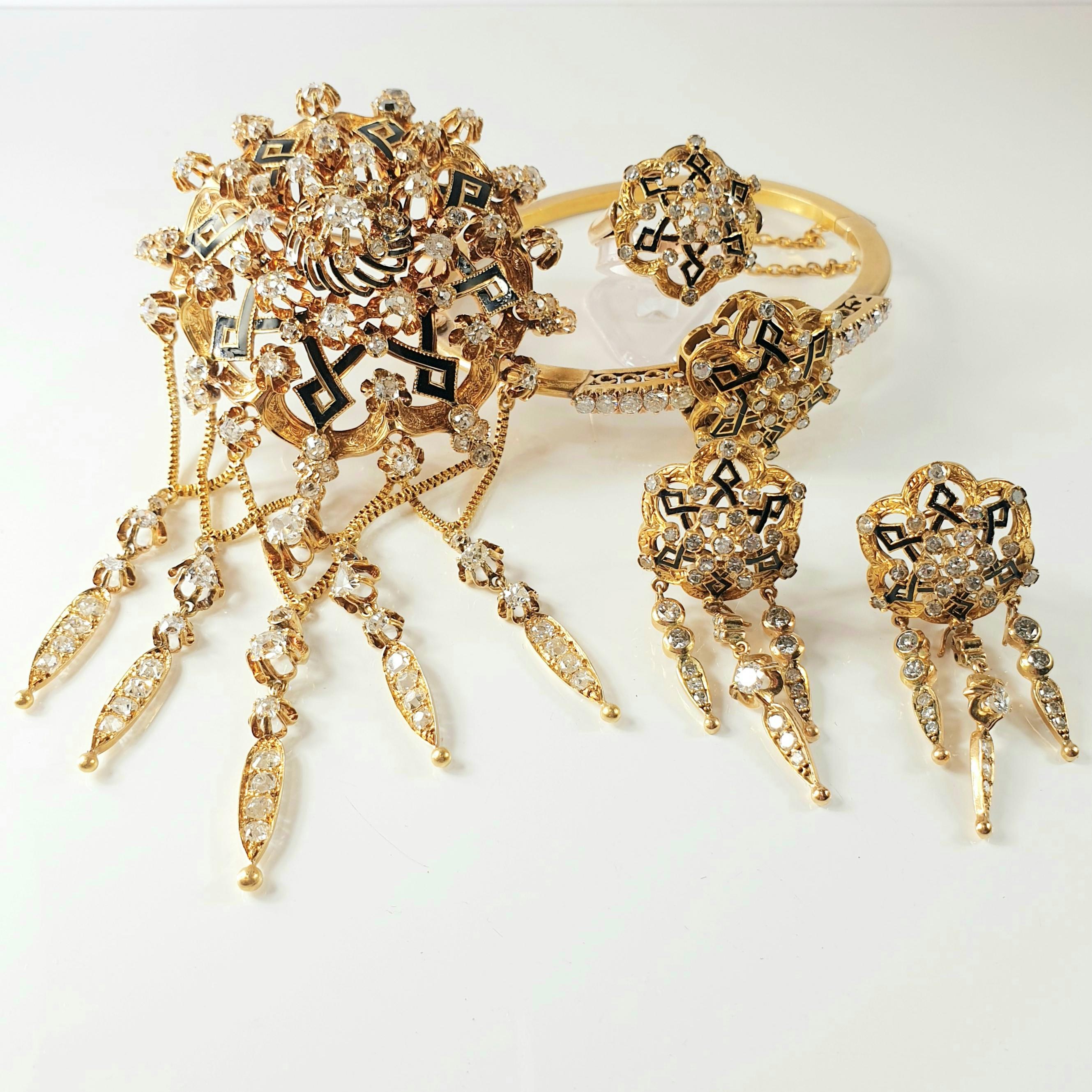 Important 1860s Spanish Elizabethan Renaissance  Brooch, Earrings and  Ring and Bracelet Jewelry Set.  
Mounted in 18kt gold with geometric motifs in enamel and diamonds 
Making a central rose with diamond fringes hanging to make a nice floral