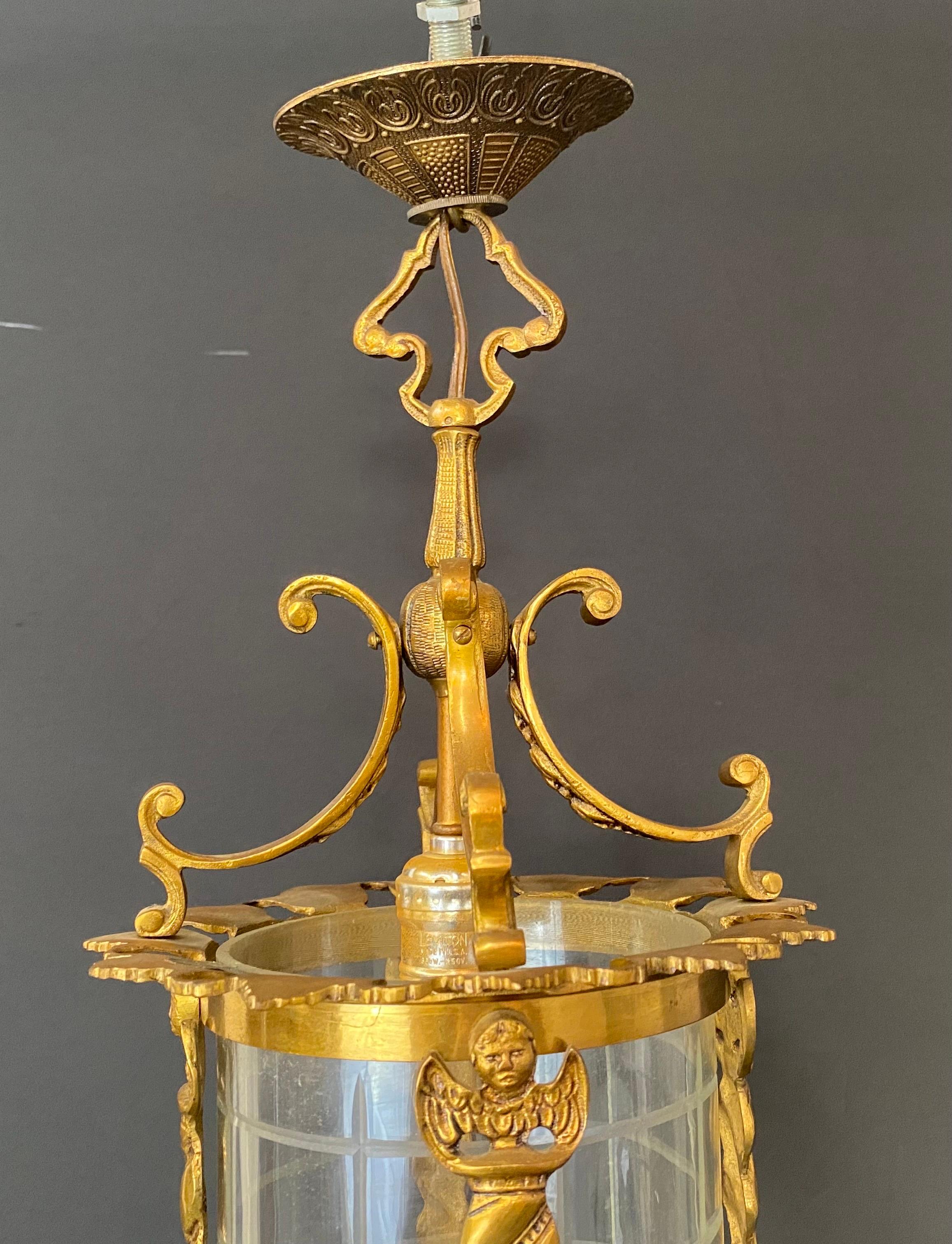 An exceptional Spanish neoclassical revival style lantern or pendant. The pendant is hand crafted of gilt iron in a cylindrical shape. Featuring  classical revival scrolls ad leaves design, the pendants shows four figural design of winged angels on