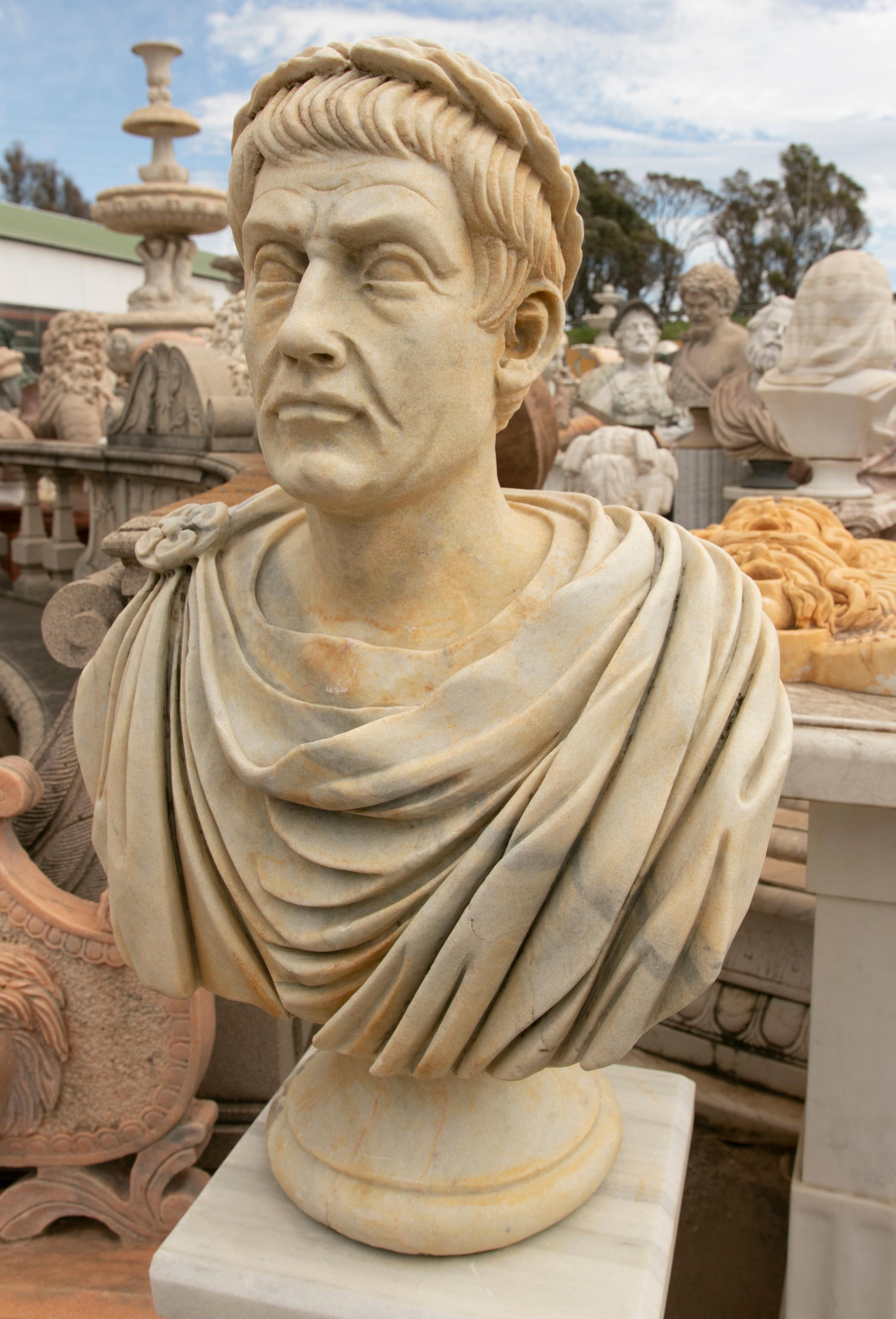 Spanish neoclassical style hand carved aged white marble bust of Roman emperor Julius Caesar wearing imperial robes and laurel wreath.