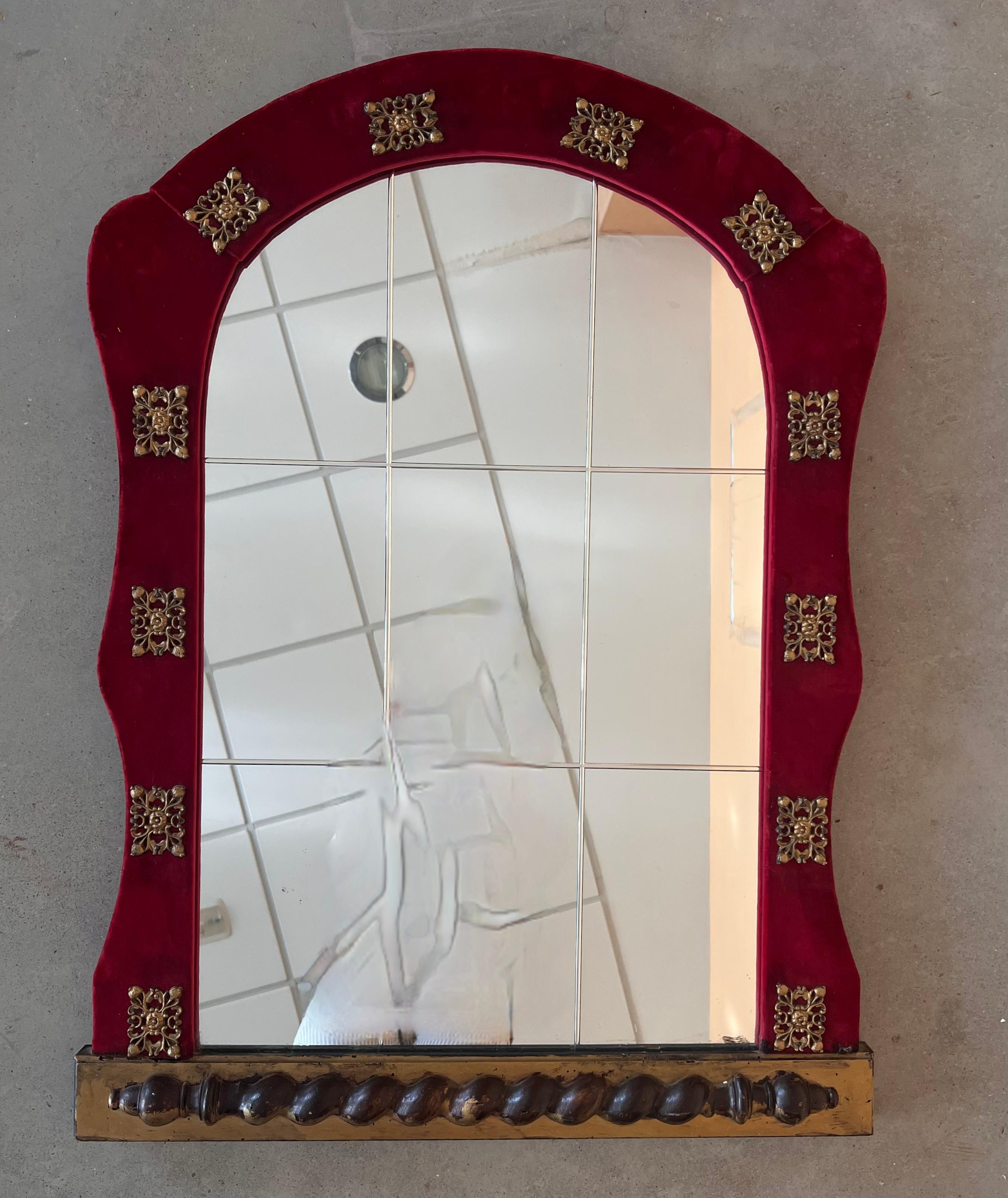 Rare Spanish Colonial wall mirror with an angular frame upholstered in antique red velvet and composed of naturally antiqued mirrored panels 
 Large, rectangular with crest form with mirror inset into frame.