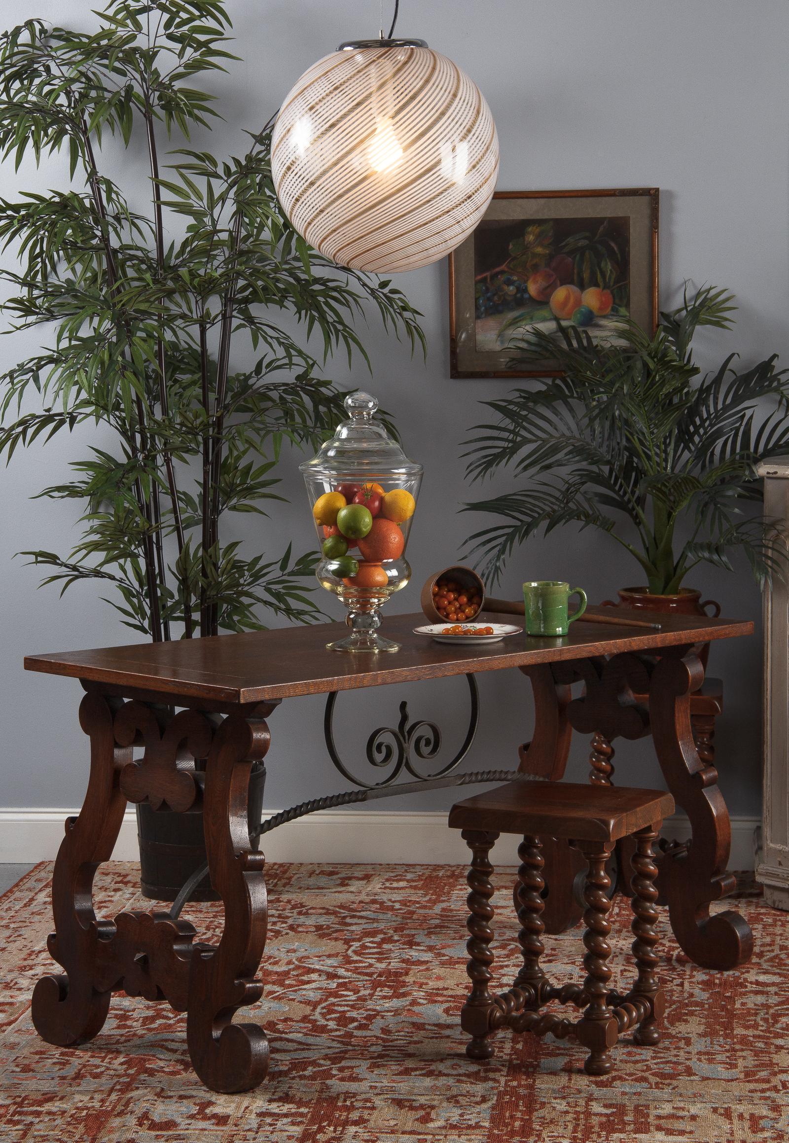 A shapely oak Spanish console table with highly decorative iron stretcher, circa 1920. Rich, warm oak with fanciful scrolling lyre-shaped legs on either side, angling in at the top in typical Spanish fashion. The legs are joined by a long iron