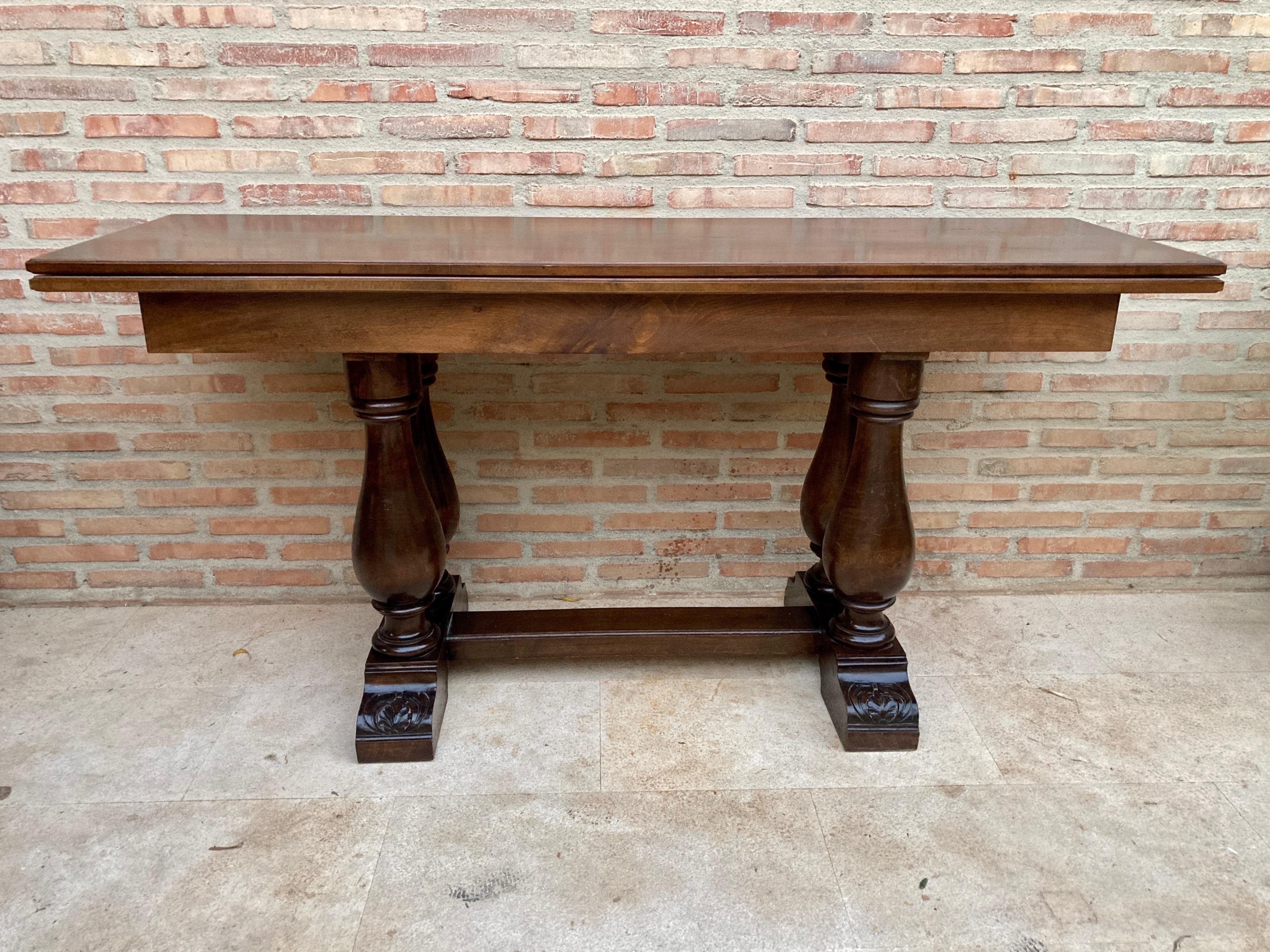 Spanish oak dining table foldable lengthwise console table with four column legs, circa 1960.
Spanish oak console table.
The longitudinal folding allows transformation into a dining table.
Its 4 column-shaped legs are carved at its base and are