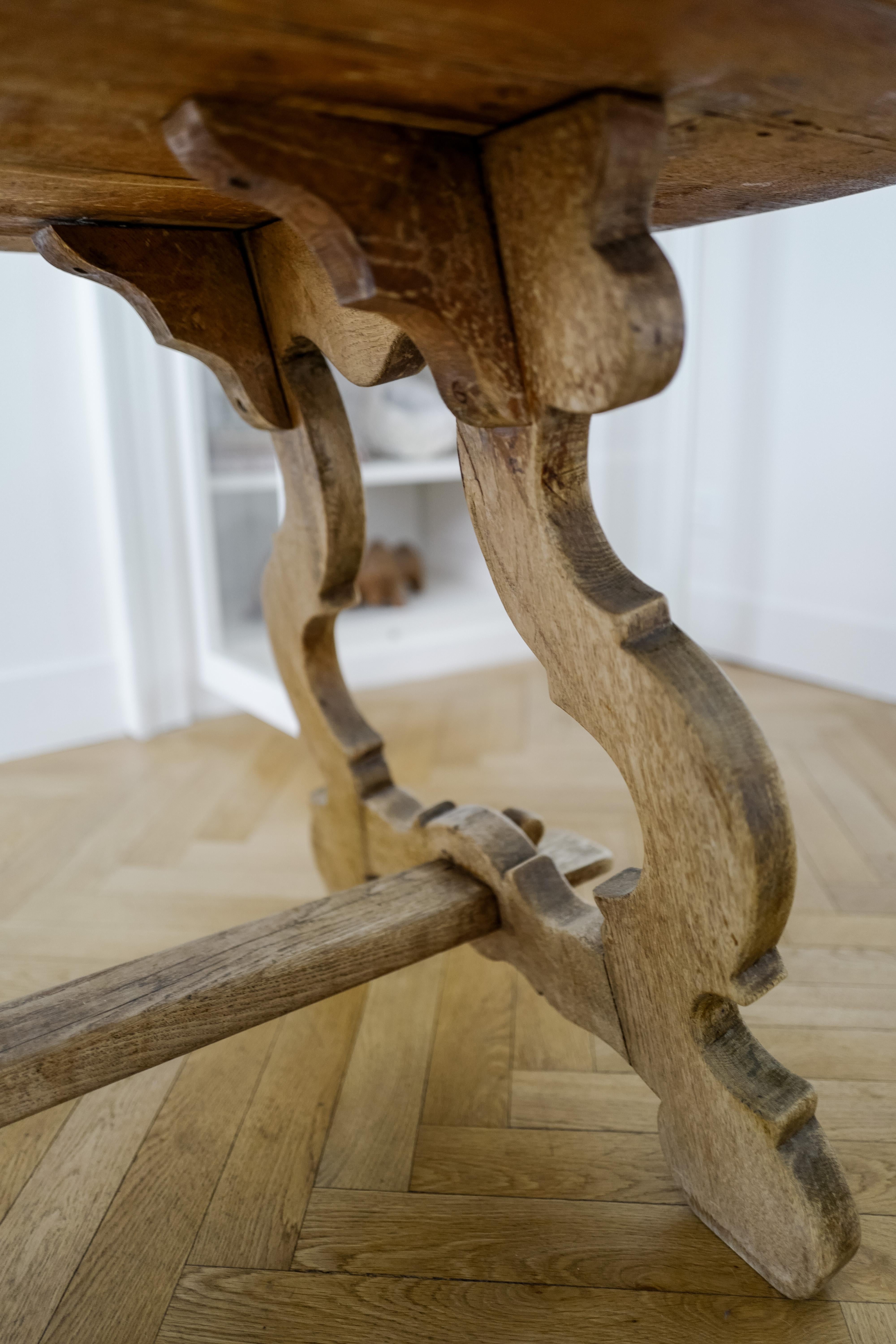 Esta mesa de caballete de roble de bella factura belga encarna el estilo de las granjas españolas del siglo XX. Su parte superior sólida y pesada añade durabilidad, mientras que el diseño plegable facilita su transporte o almacenamiento. La base se