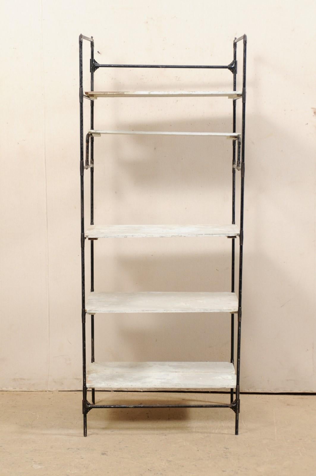 A Spanish artisan created tall open shelving unit from the mid-20th century. This vintage rack from Spain, standing just over 6 feet in height and approximately 30 inches deep, features painted wood shelves resting within a metal frame. This storage