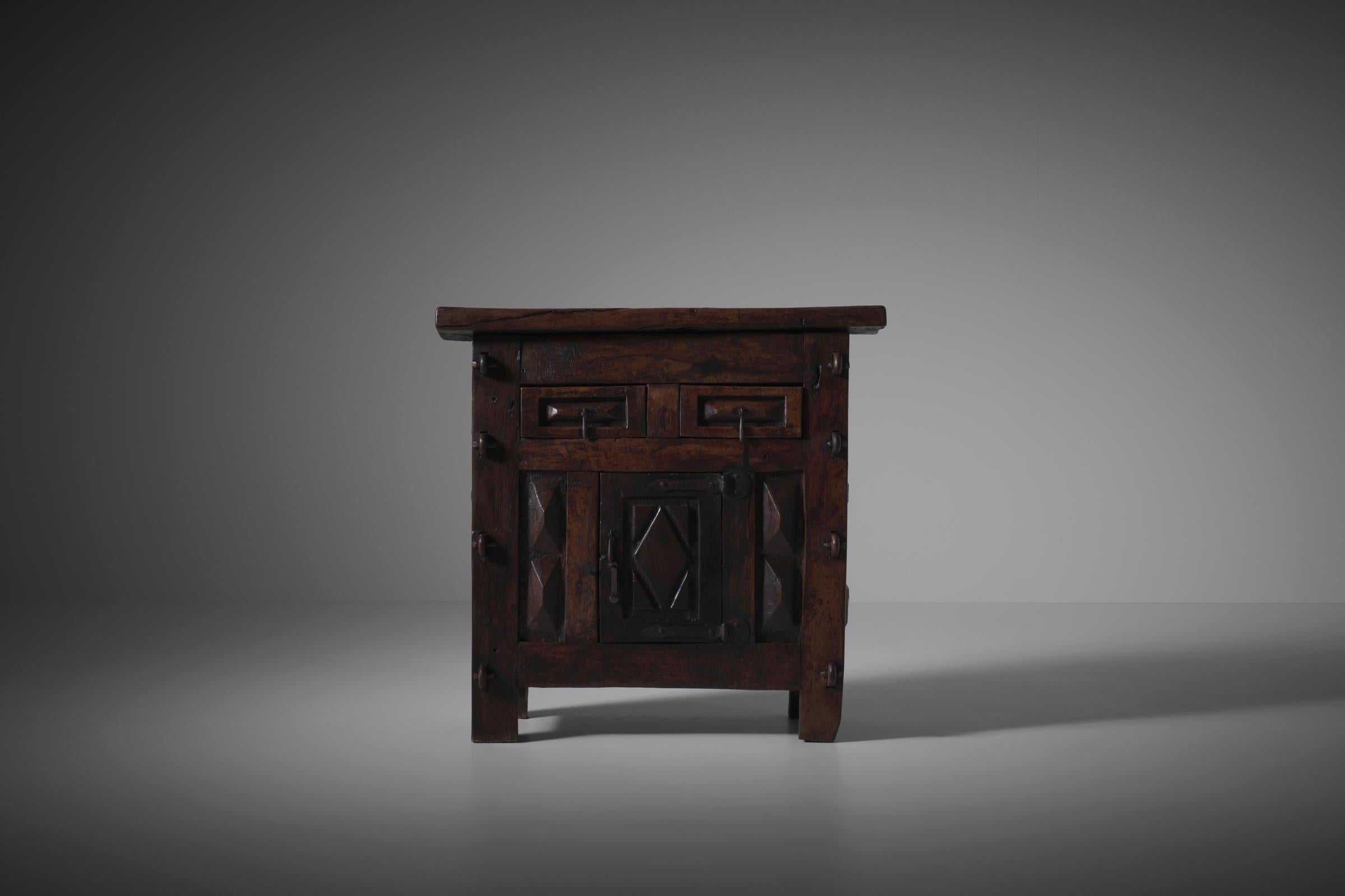 Beautiful Spanish dark wooden cabinet from the 19th century with interesting textured details. All is hand crafted / carved out of solid wood and forged metal such as the primitive yet elegant forged iron handles and hinges. The cabinet offers one