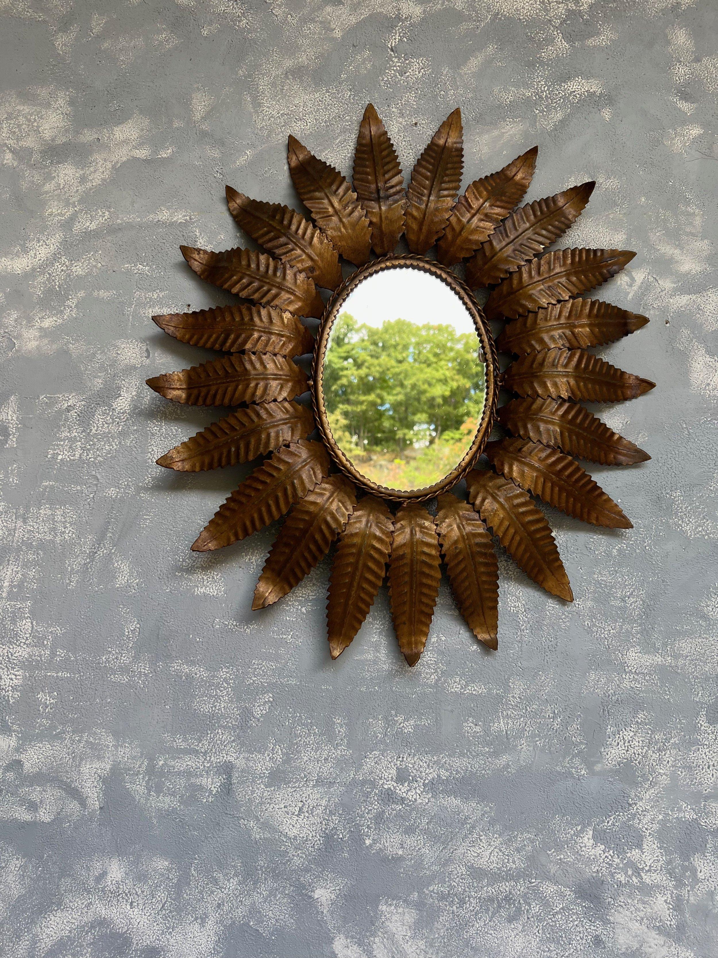 An exceptional Spanish 1950s oval sunburst mirror. This unusual mid-century oval sunburst mirror is a unique and stunning piece of decor. The evenly spaced rays or leaves surrounding the braided interior frame give it a distinctive and eye-catching