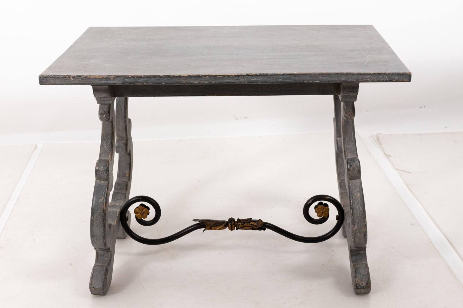 Spanish carved rectangular accent table with scrolled Iron cross stretcher and gilded detail, circa 1960s. The piece also features a trompe l'oeil blue stone painted top with gray/blue finish. Please note of wear consistent with age including